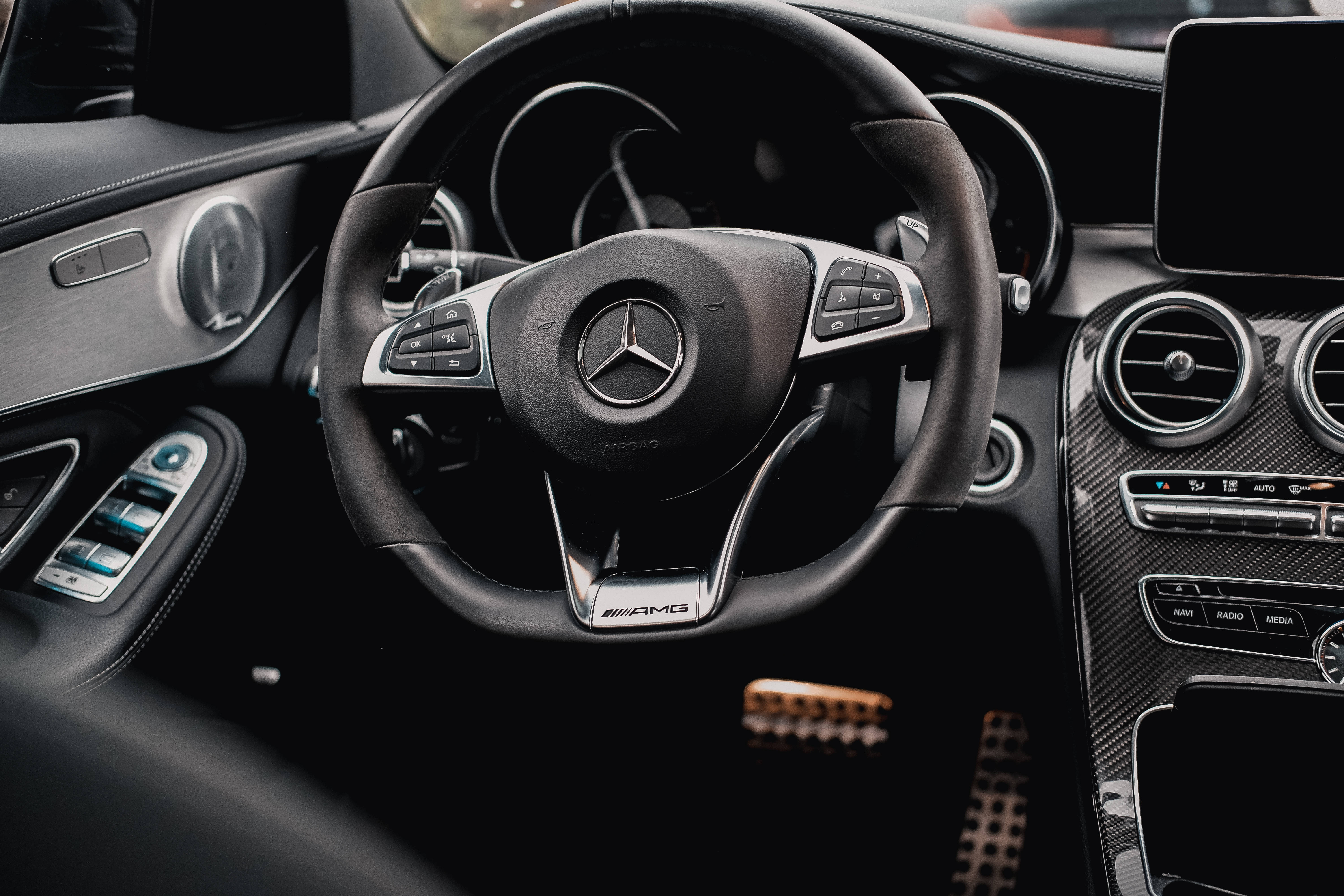 Mercedes Amg 桌布 壁紙 — 近距離拍攝時尚黑色 Mercedes-AMG 方向盤，帶有碳纖維裝飾和數位儀表板。