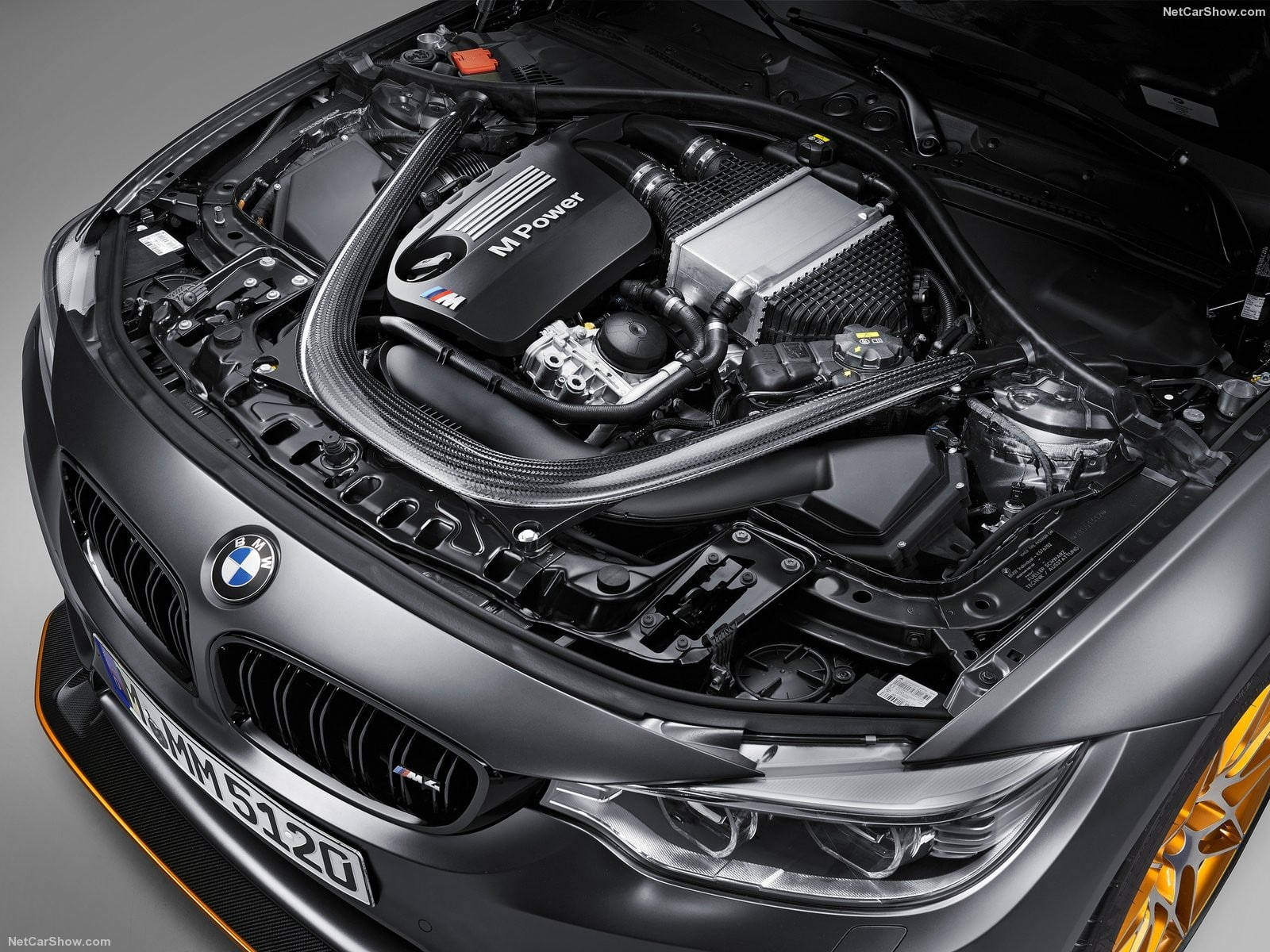 黑色BMW M Power跑車引擎艙，帶有橙色點綴和拋光部件。