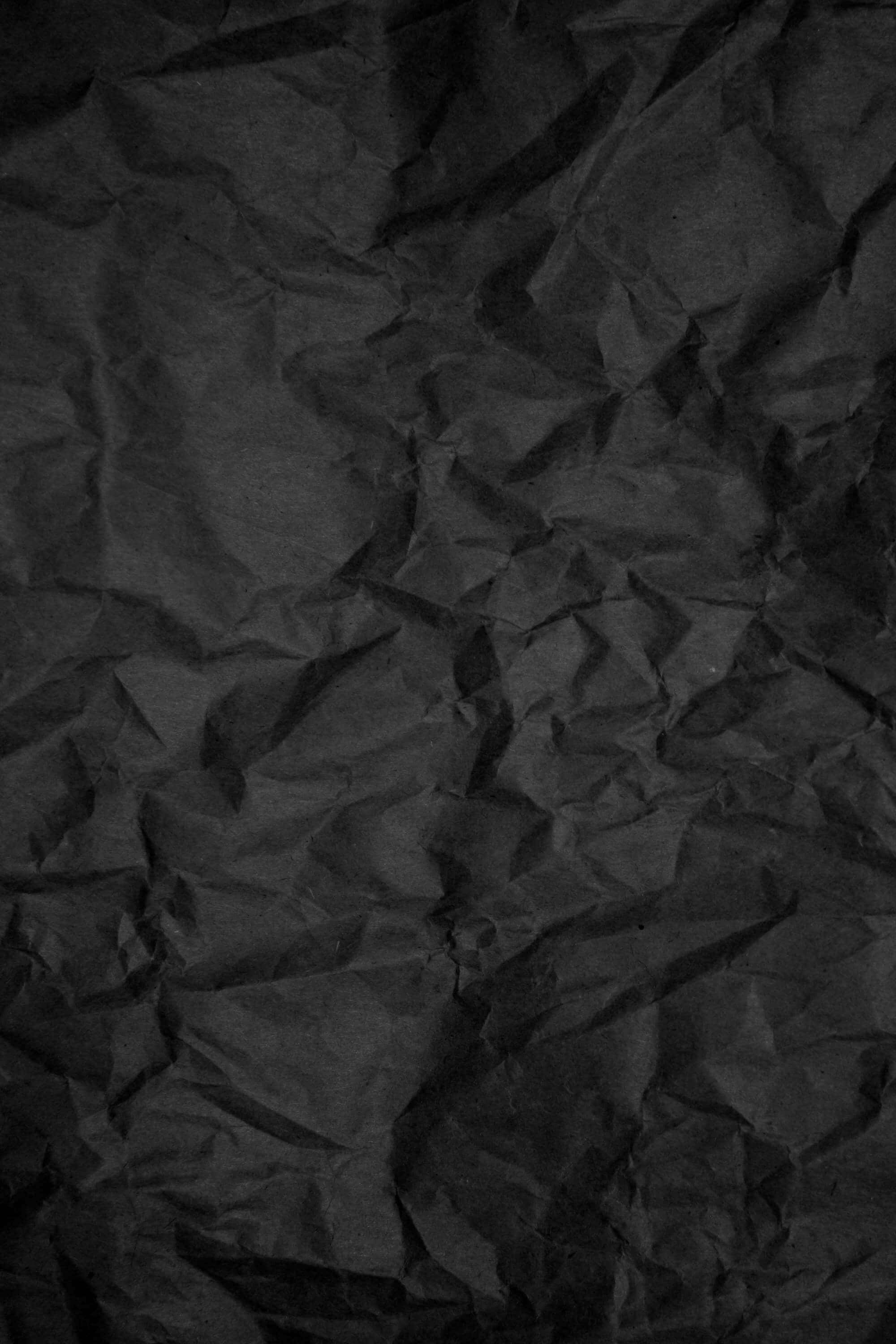 Black Paper Texture 桌布 壁紙 — 近距離拍攝深度皺摺的黑色紙張，帶有紋理陰影和高光。