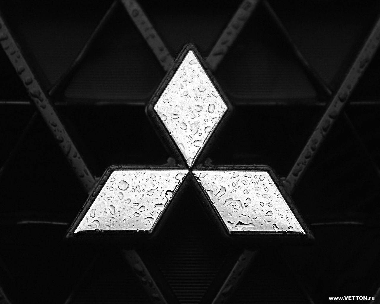 Mitsubishi 桌布 壁紙 — 近距離拍攝濕潤的三菱標誌，水滴在鍍鉻表面上閃閃發光，背景為深色紋理。
