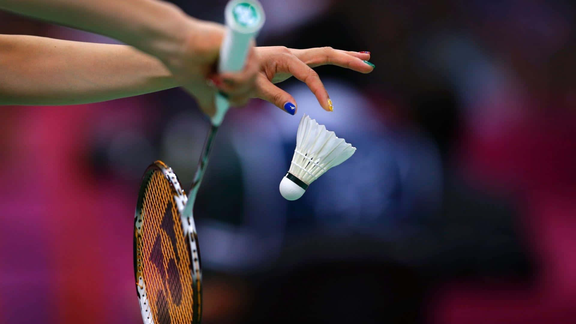 HD Badminton 桌布 壁紙 — 近距離拍攝球員的手緊握羽毛球拍，而羽毛球在比賽期間懸浮在半空中。