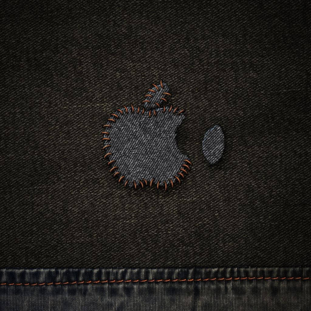 Denim 桌布 壁紙 — 近距離拍攝的Apple標誌，以橙色線縫在深色牛仔布上，背景為有紋理的布料。