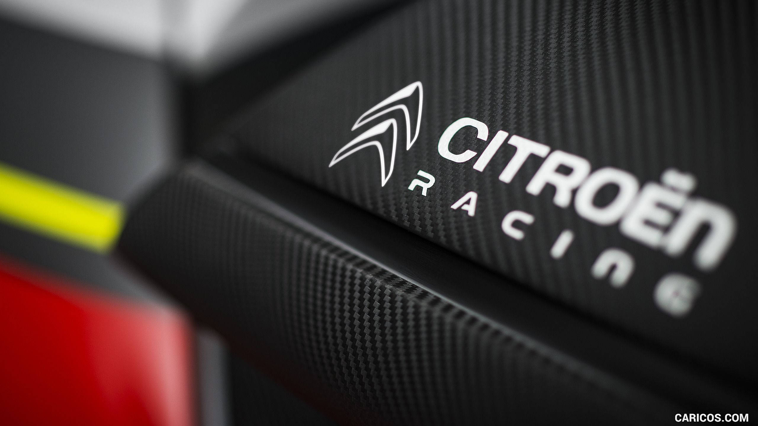 雪鐵龍 桌布 壁紙 — 近距離拍攝的Citroën Racing標誌，位於有紋理的黑色碳纖維上，配以銳利的白色字體和鮮豔的黃紅色點綴。