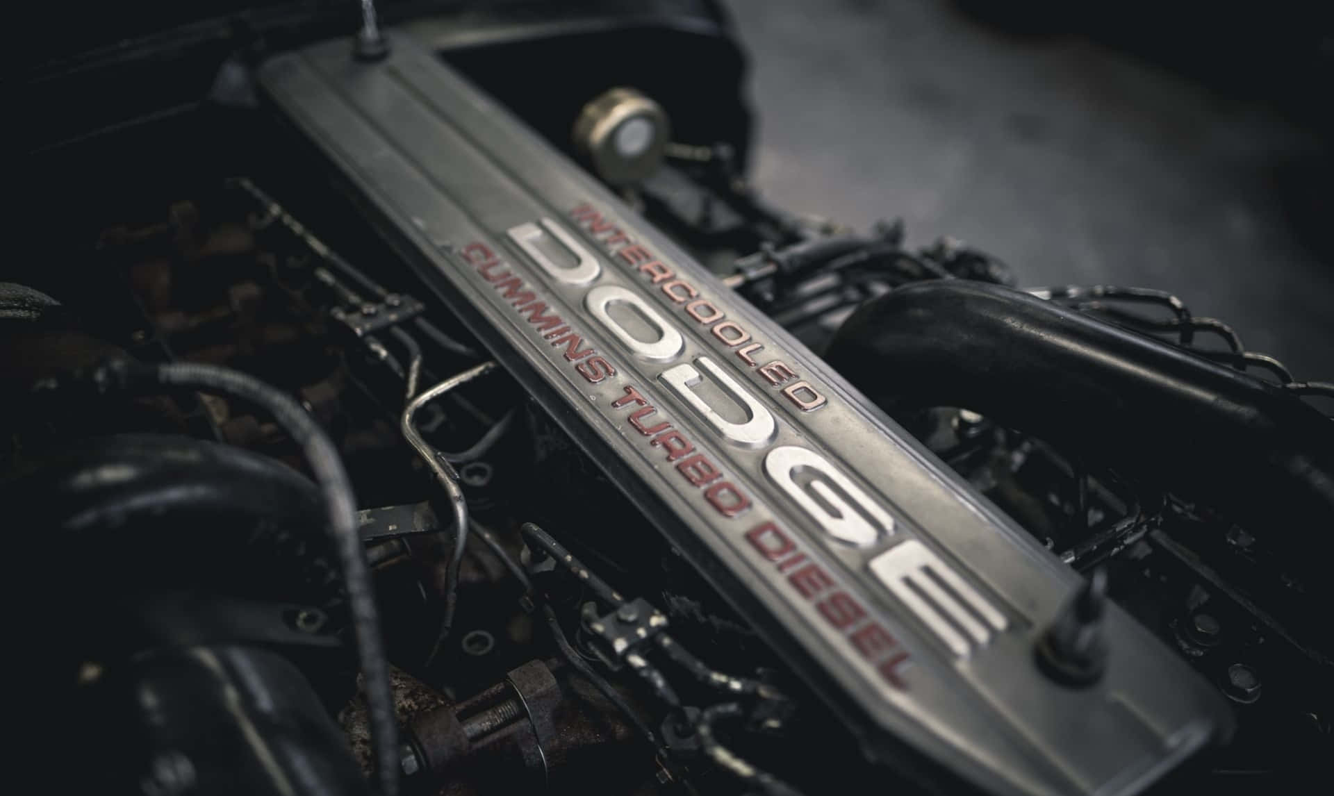 Dodge 桌布 壁紙 — 近距離拍攝的Dodge Cummins Turbo Diesel引擎，帶有金屬閥蓋和複雜的機械細節，在昏暗燈光下。