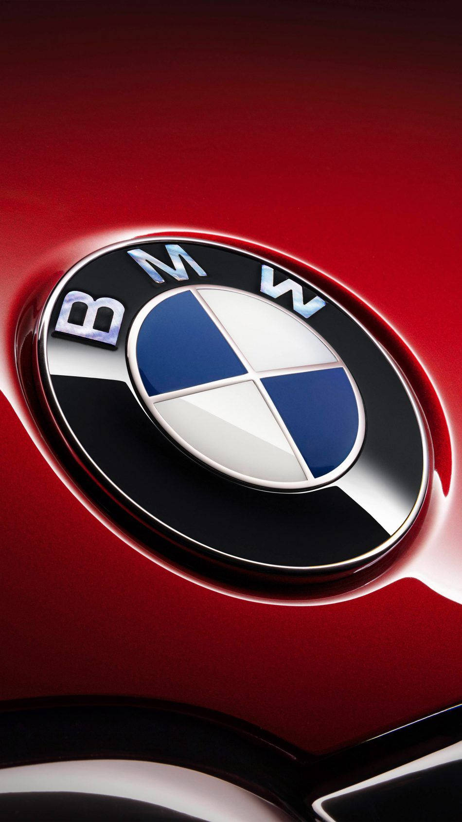X 桌布 壁紙 — 近距離拍攝的亮面紅色BMW標誌，帶有藍白相間的區域，反射工作室燈光。