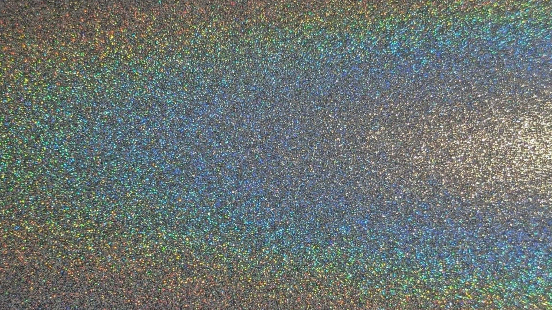 High Resolution Glitter 桌布 壁紙 — 近距離拍攝的彩虹色閃粉，在深色紋理背景上呈現變幻的彩虹色調。