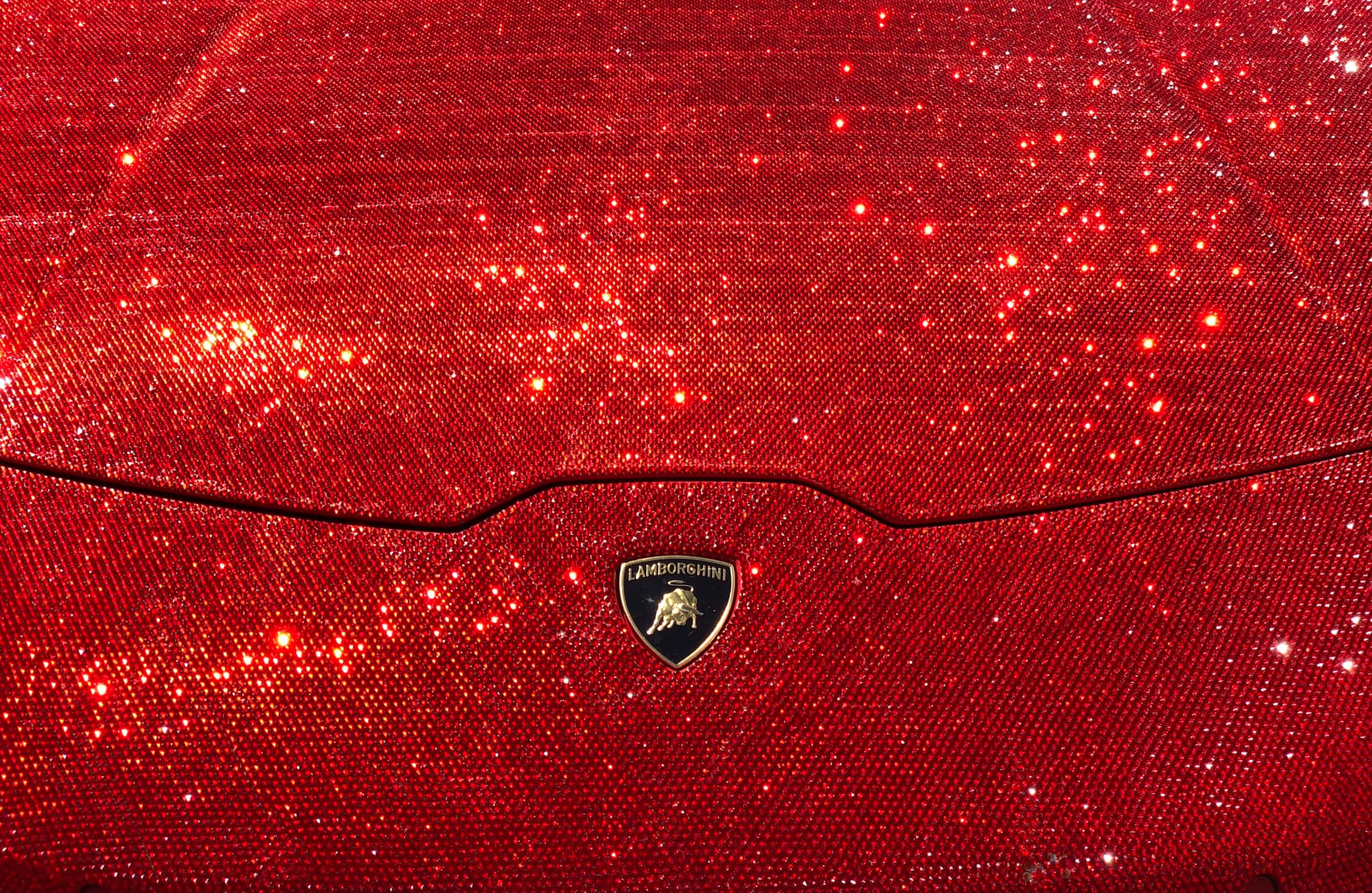 Red Glitter 桌布 壁紙 — 近距離拍攝的鮮紅色亮粉覆蓋的藍寶堅尼引擎蓋，中央帶有標誌性的公牛徽章。