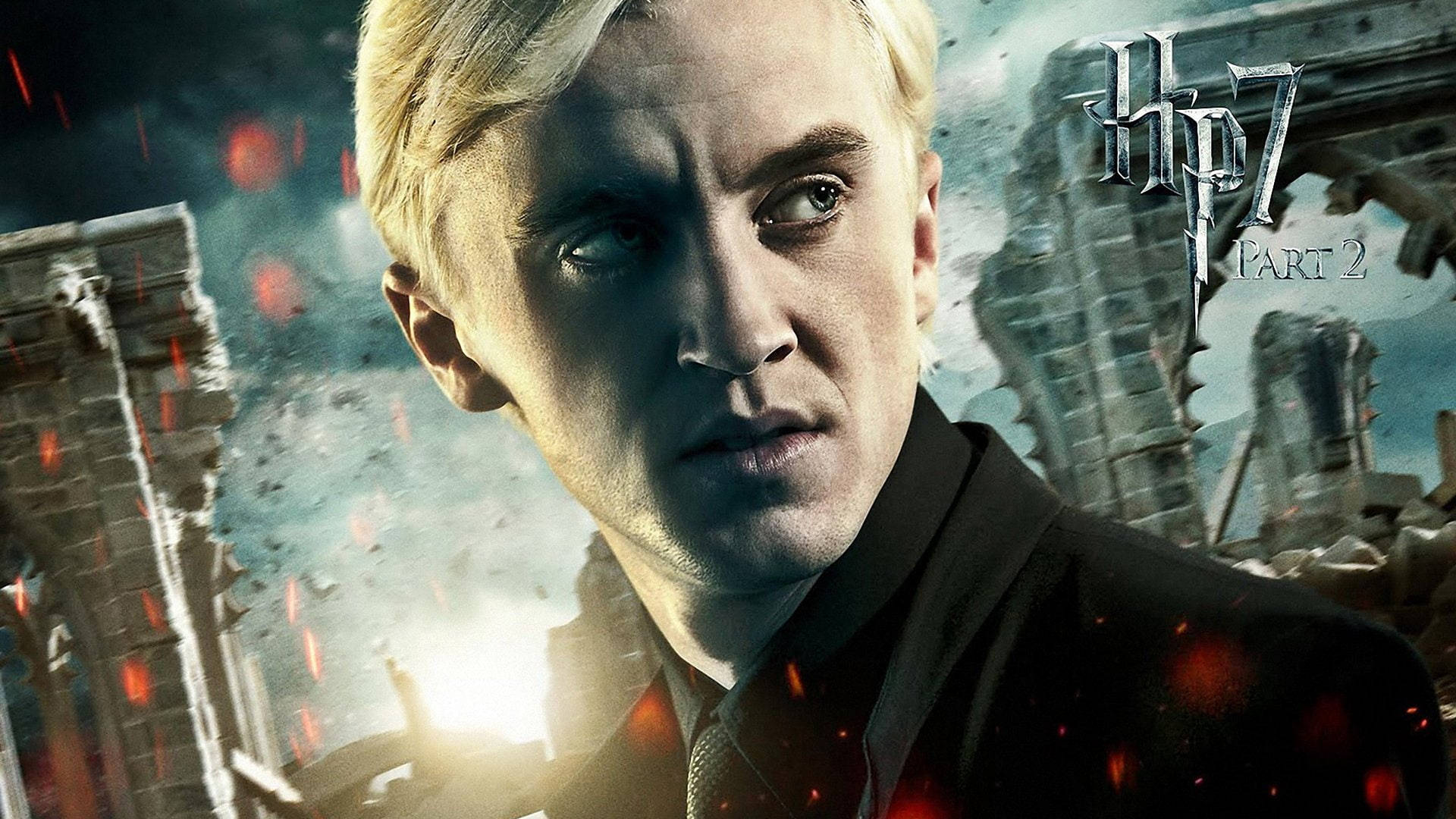 draco 桌布 壁紙 — 近距離拍攝身穿深色西裝的Draco Malfoy，背景是 crumbling 城堡，熾熱的紅色火花飛舞。
