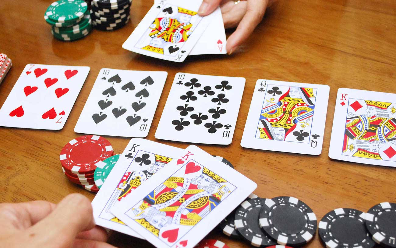 Playing Cards 桌布 壁紙 — 近距離拍攝雙手在木桌上玩撲克牌，有彩色紙牌和籌碼堆。
