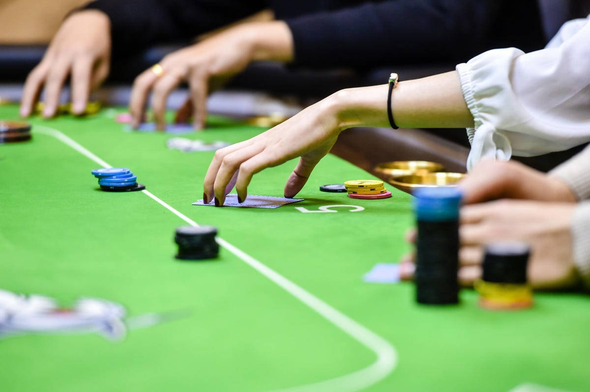 Playing Cards 桌布 壁紙 — 近距離拍攝雙手在綠色氈桌上玩撲克牌，桌上擺放著色彩繽紛的籌碼和紙牌。