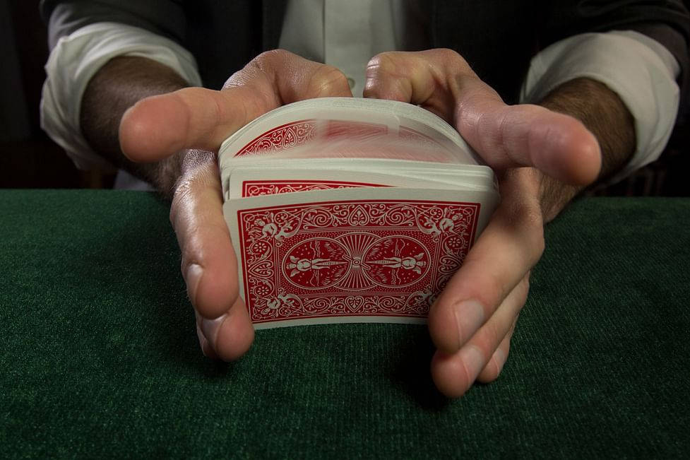 Playing Cards 桌布 壁紙 — 近距離拍攝雙手熟練地操控一副紅色背面的撲克牌在綠色絨面之上。
