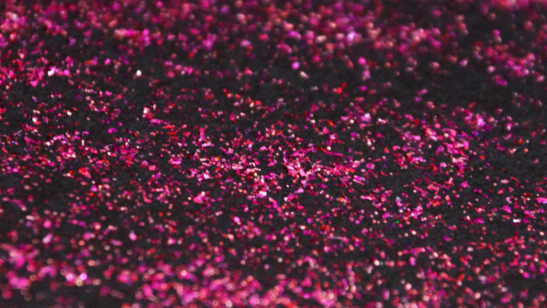 Dark Pink 桌布 壁紙 — 近距離拍攝鮮豔的粉紅色和紅色亮粉散落在深色紋理表面上，在燈光下閃閃發光。