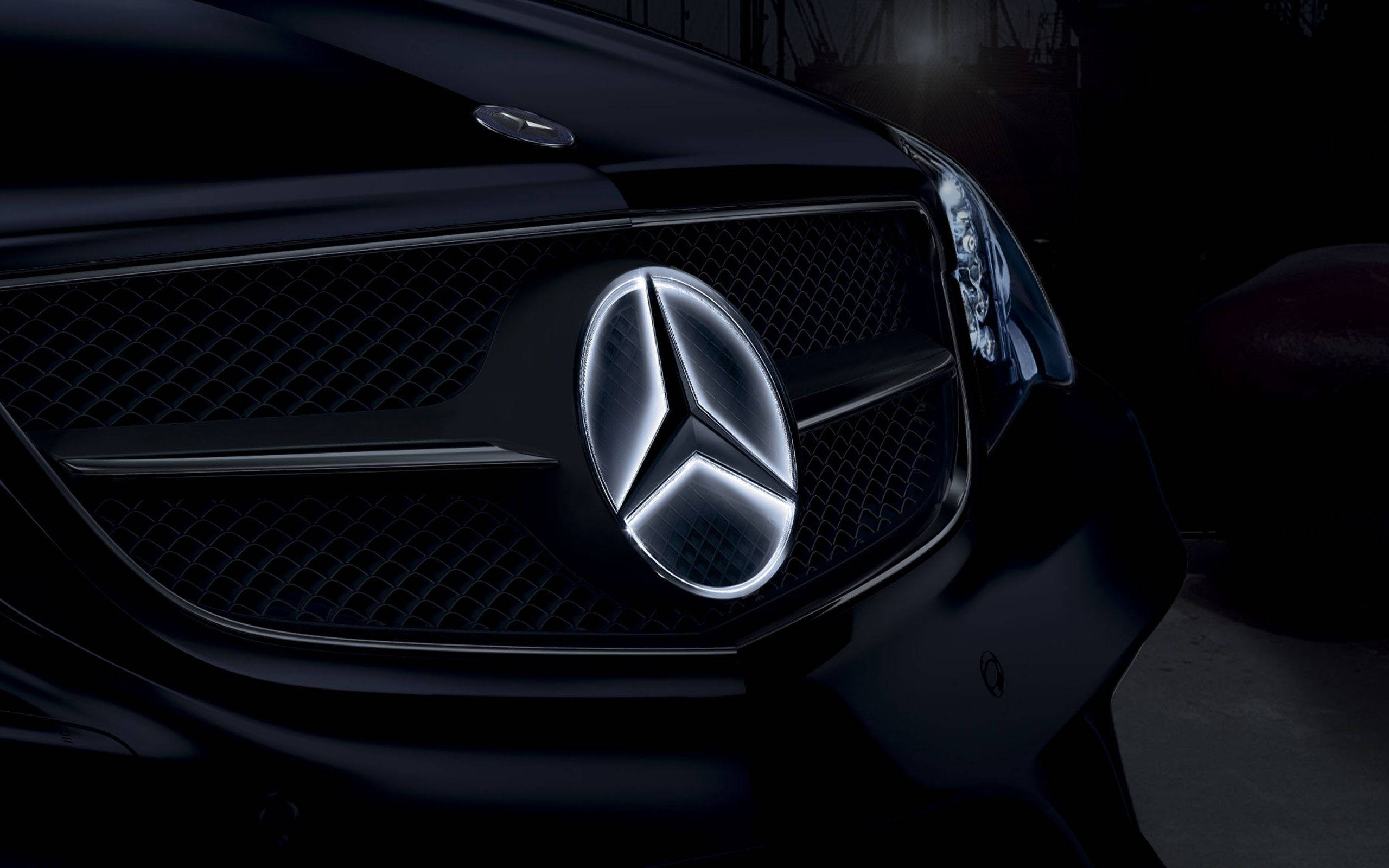 Mercedes 桌布 壁紙 — 近距離拍攝黑色賓士水箱護罩，帶有發光星徽，在戲劇性的低光照明下。
