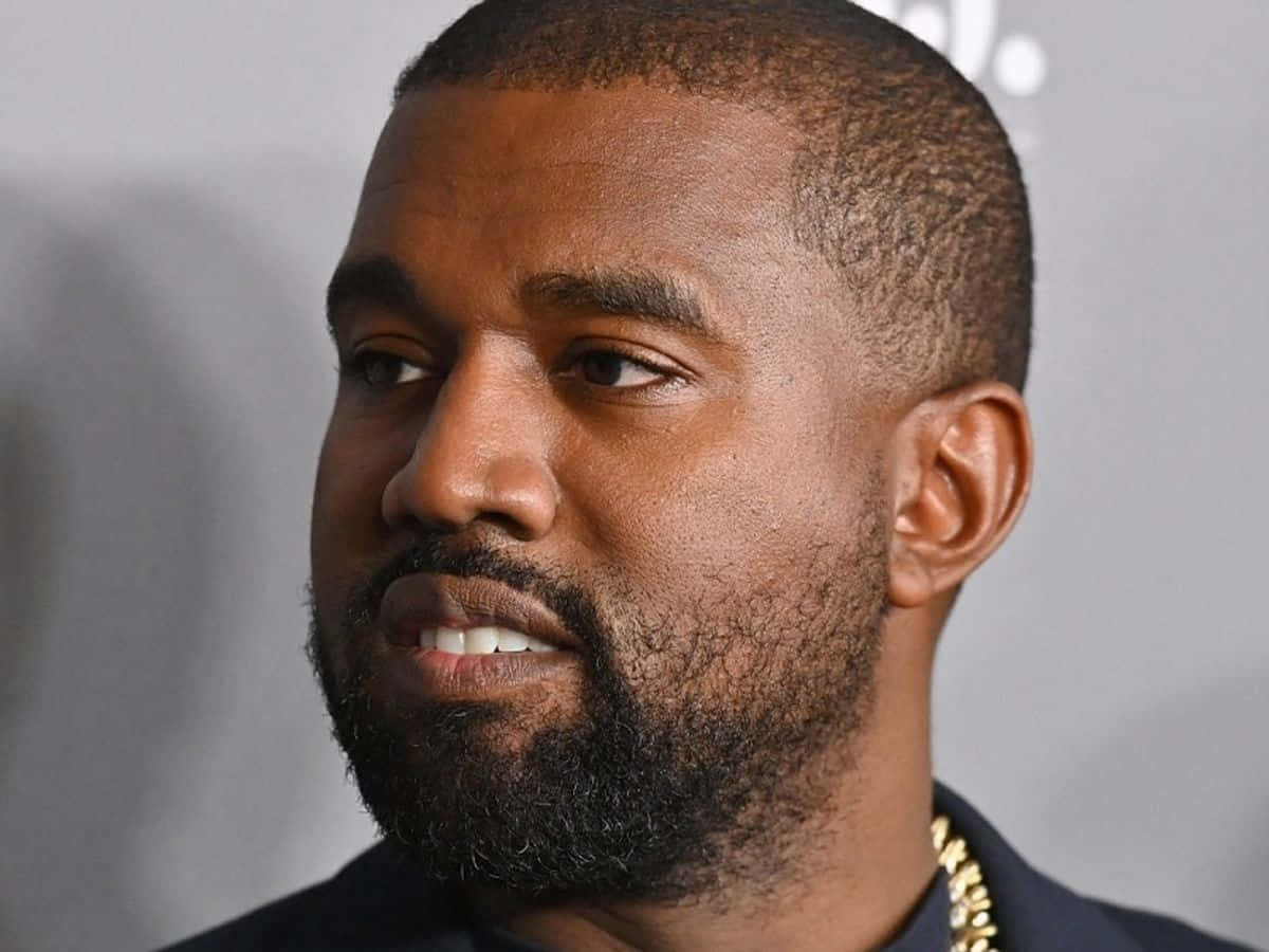 Celebrity 桌布 壁紙 — 近距離肖像，一名留鬍鬚的男子戴著金鏈，背景為中性灰色。