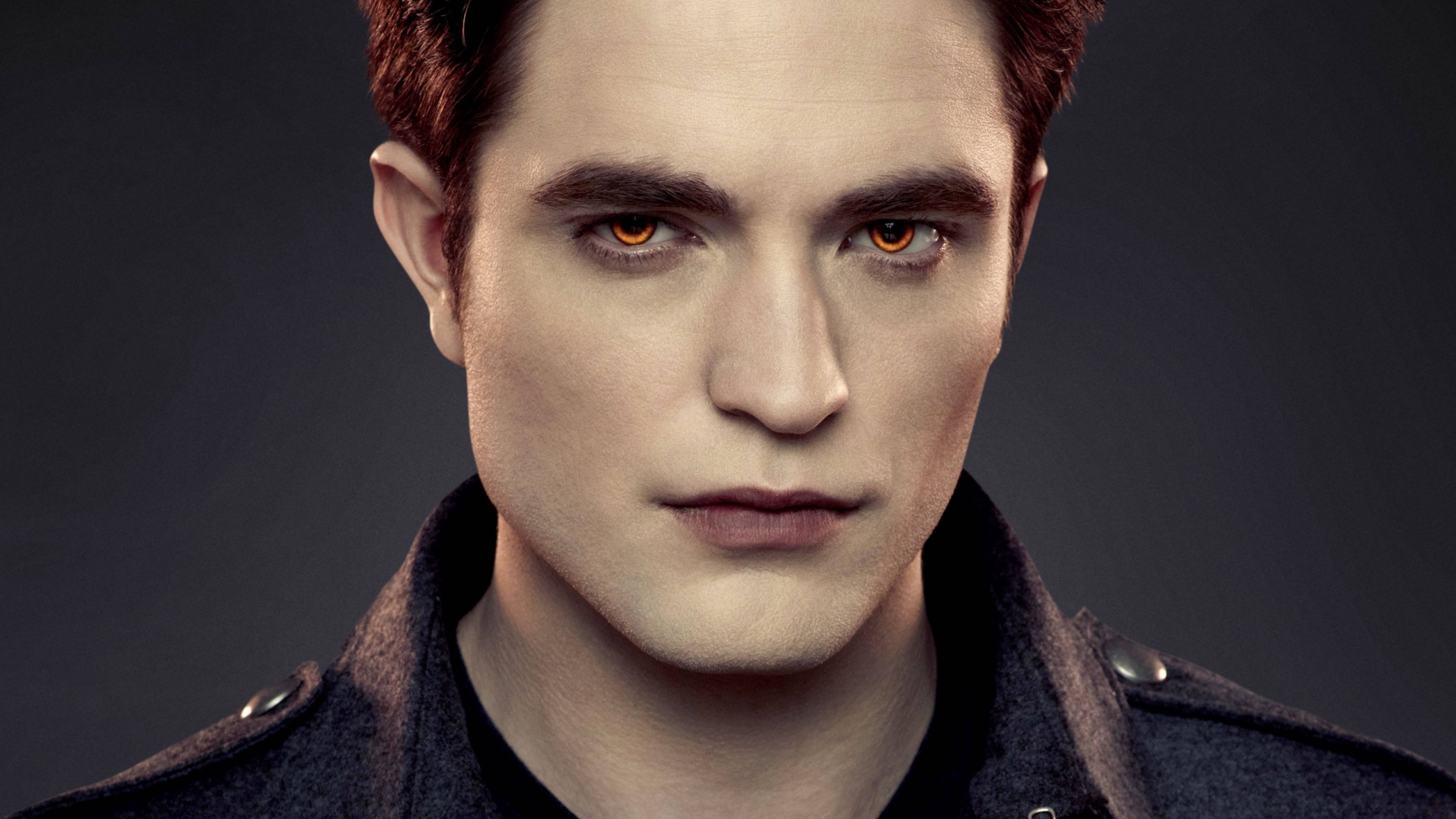 Robert Pattinson 桌布 壁紙 — 近距離肖像照，一名男子擁有強烈的琥珀色眼睛和深色外套，背景為柔和的灰色。