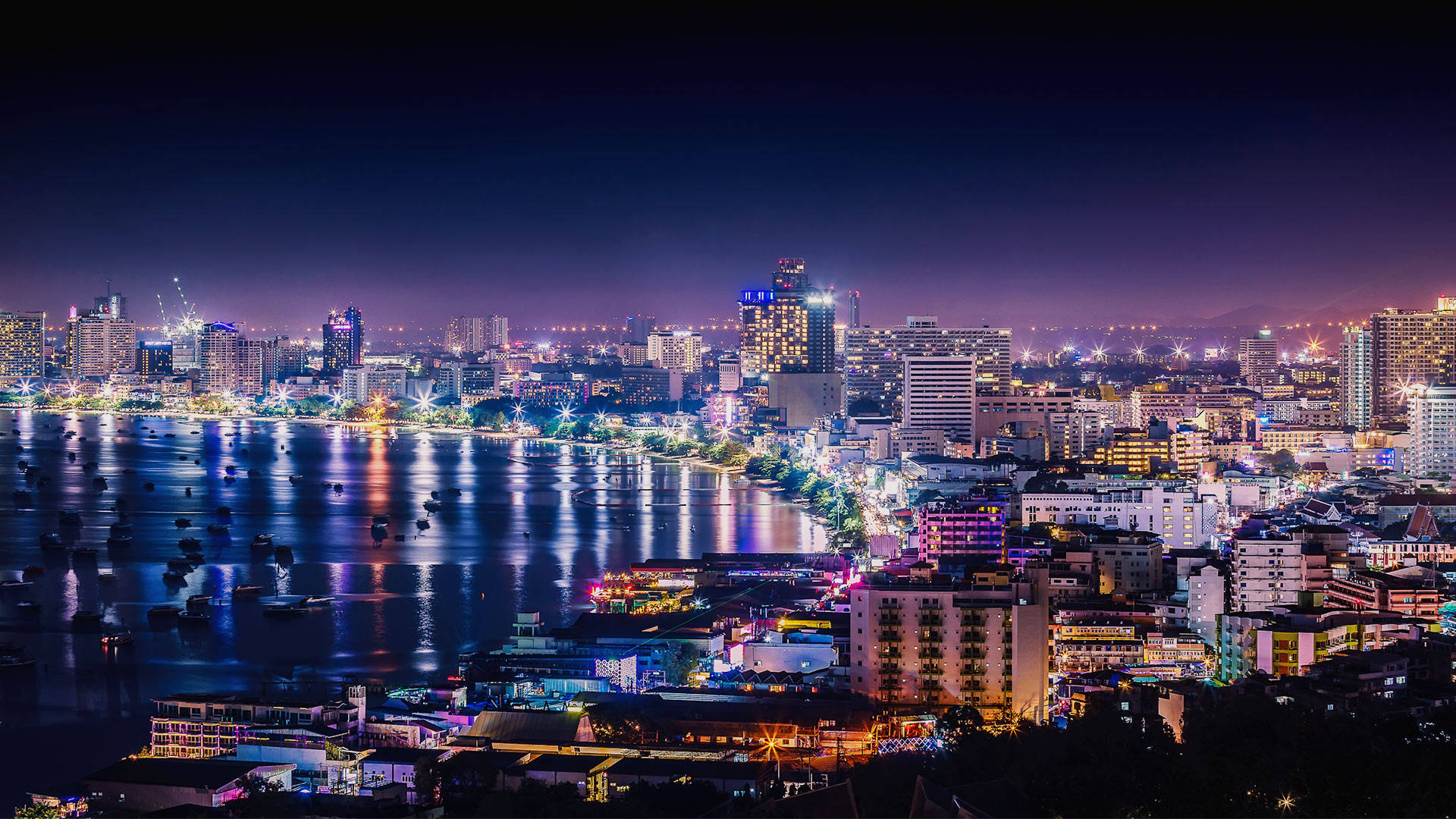 夜空 桌布 壁紙 — 迷人的夜景城市景觀，閃爍的摩天大樓和充滿活力的燈光倒映在平靜的水道上。