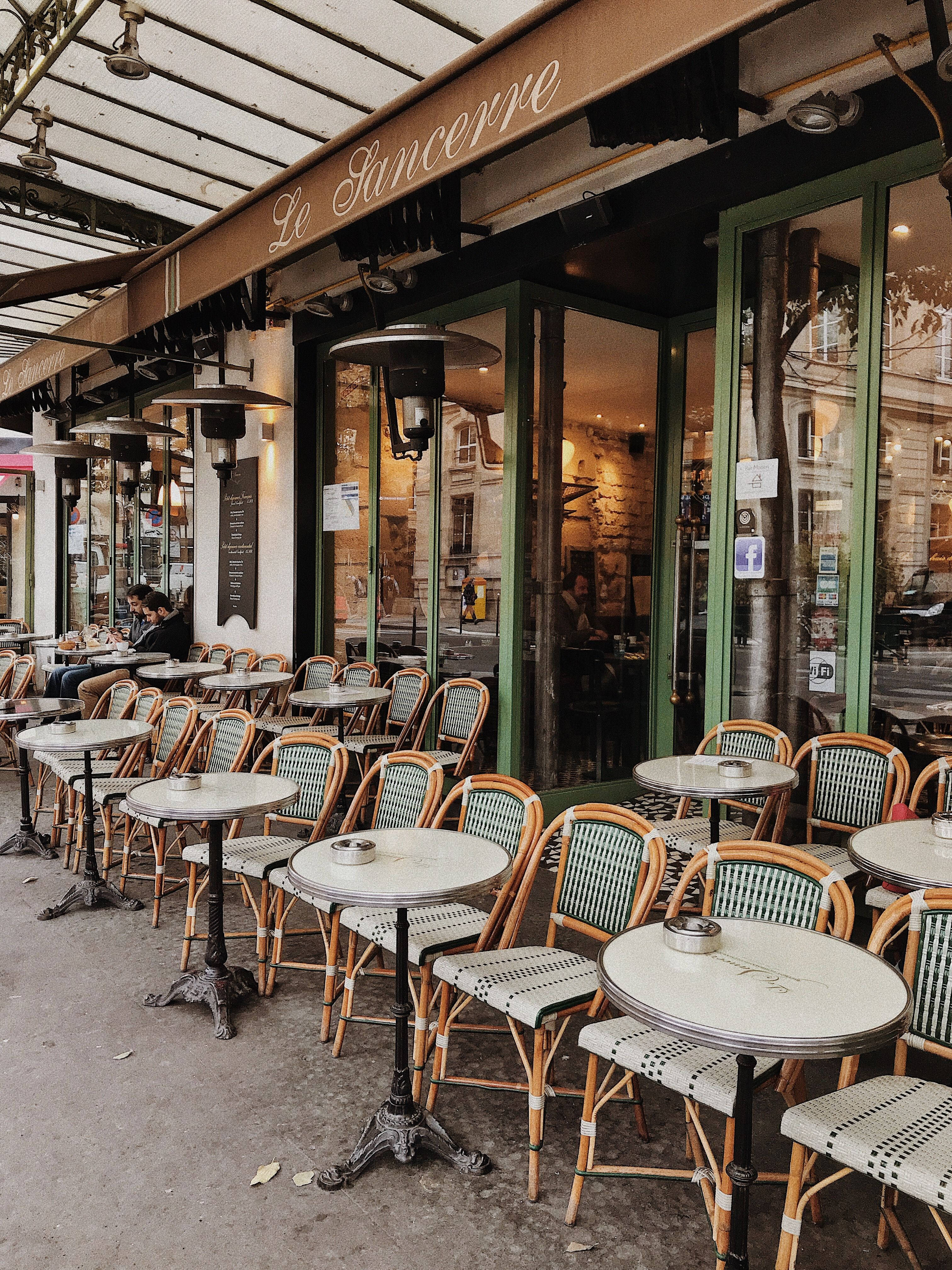 France 桌布 壁紙 — 迷人的巴黎咖啡館露台，配有經典藤椅和大理石桌面，上方有玻璃天篷。