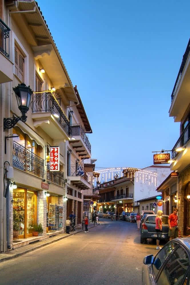 Town 桌布 壁紙 — 迷人的歐洲街道在黃昏時分，商店和陽台散發溫暖的光芒，映襯著清澈的藍天。