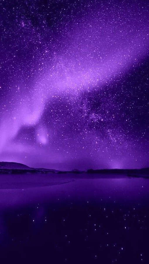 Sea 桌布 壁紙 — 迷人的紫色極光在繁星點點的夜空上舞動，倒映在平靜的湖面上，遠方有山丘。