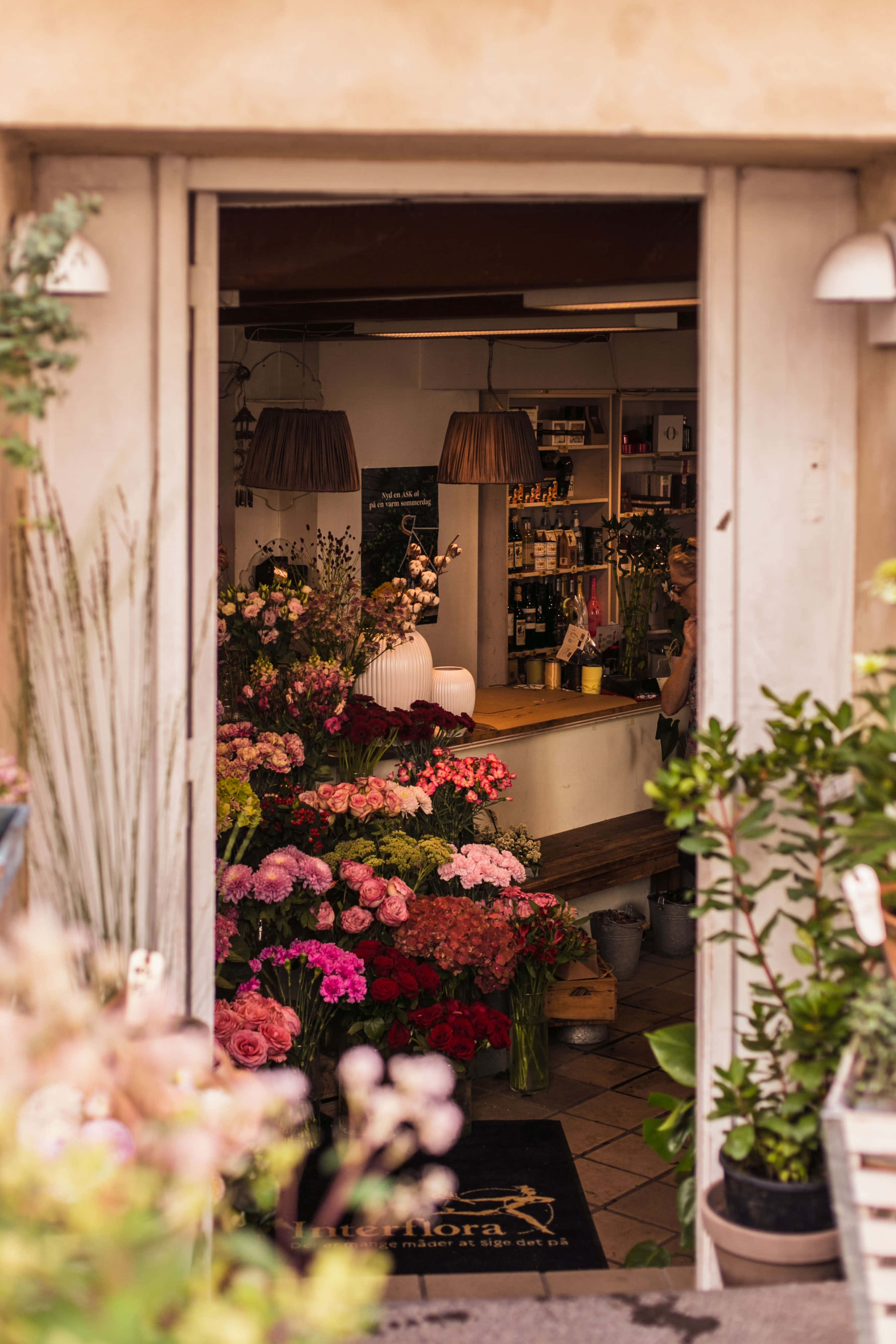 Flower Shop 桌布 壁紙 — 迷人的花店門口展現出色彩繽紛的花束和質樸的室內，沐浴在溫暖的金色光芒中。