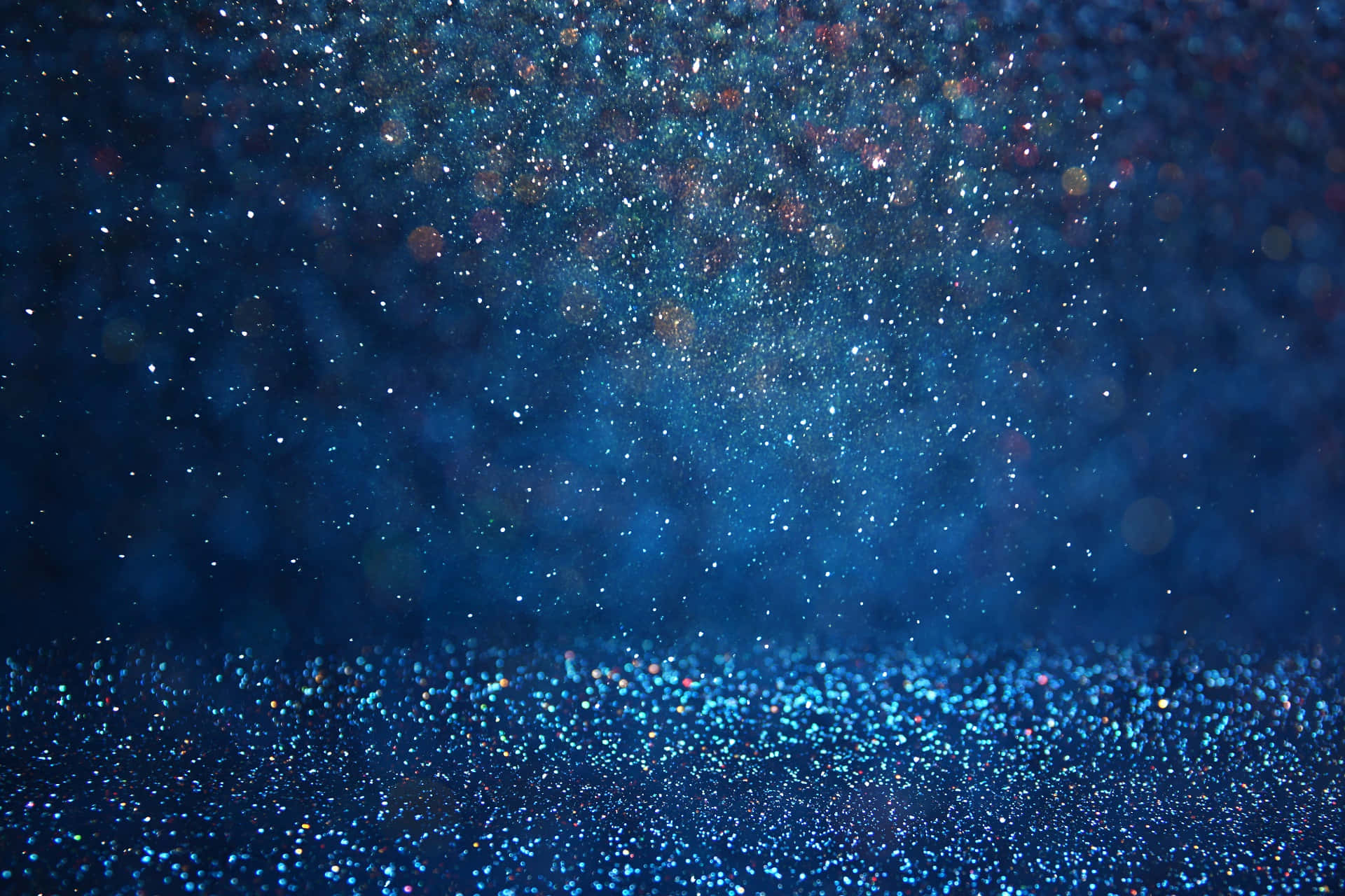 Blue Sparkle 桌布 壁紙 — 迷人的藍色閃粉背景，閃爍的粒子漂浮在柔和的散景光中。