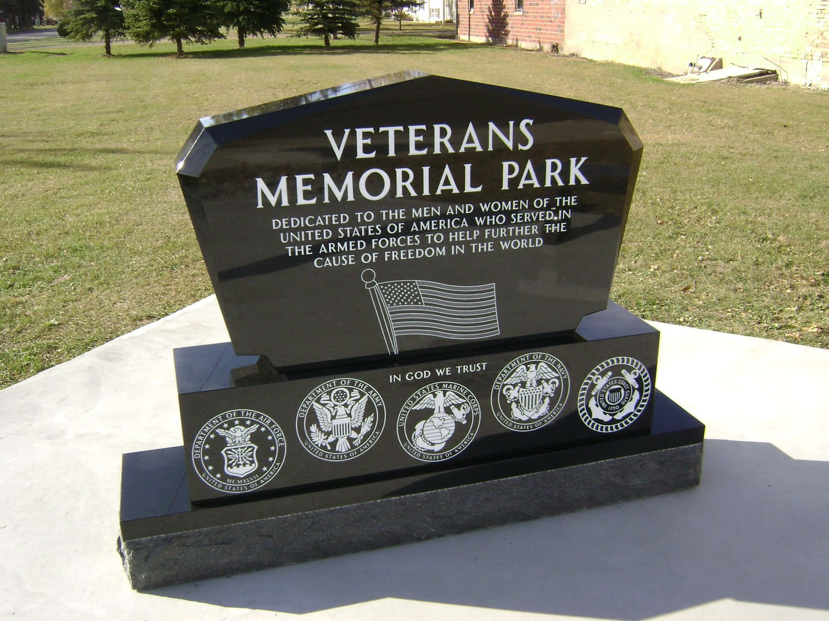 Memorial 桌布 壁紙 — 退伍軍人紀念公園中一座拋光的黑色花崗岩紀念碑，在明亮的日光下以雕刻文字和軍事徽章向美國服役人員致敬。