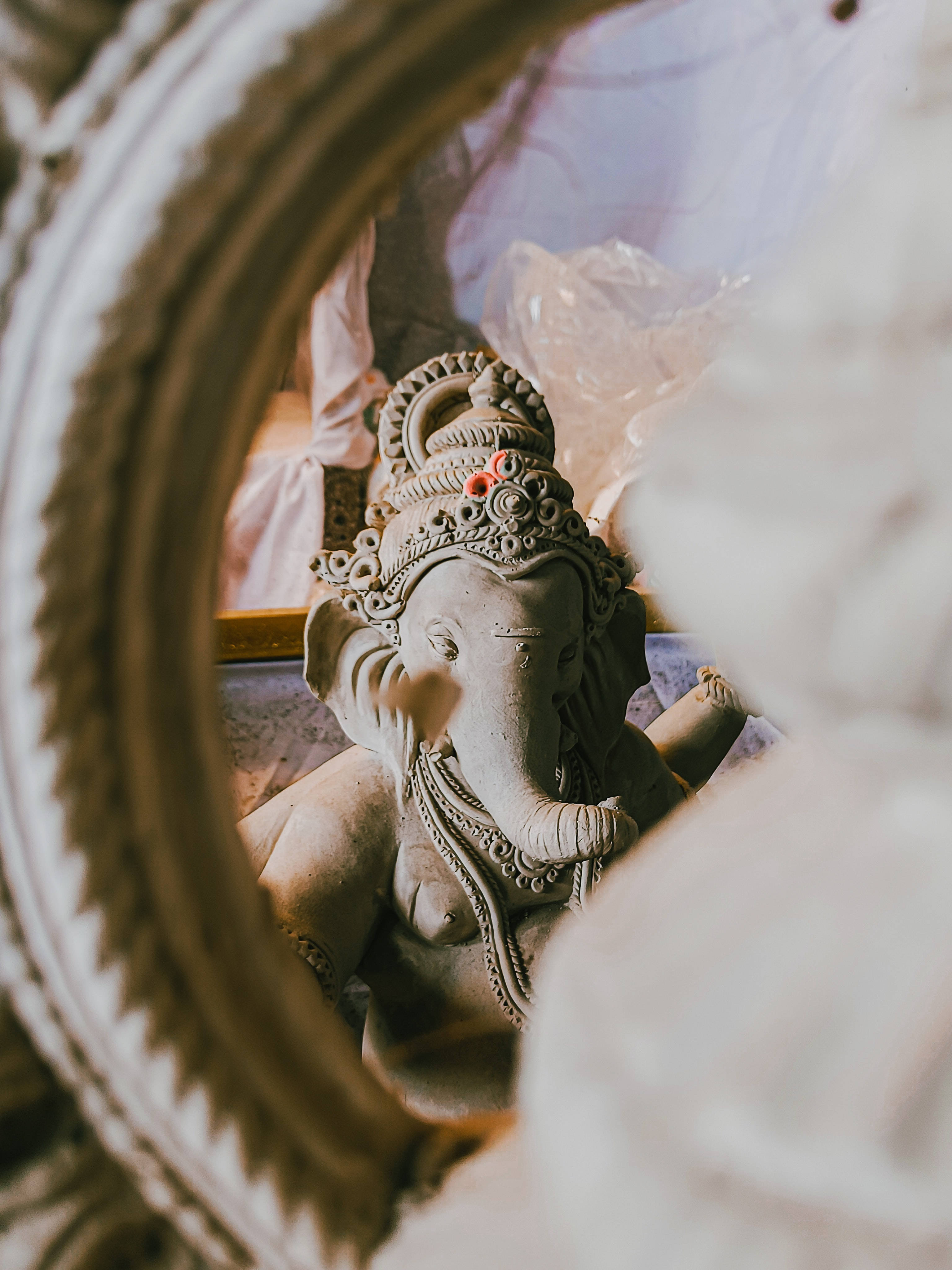 ganesh 4K 桌布 壁紙 — 透過圓形華麗框架，柔和散射光線下的一座寧靜石雕象神像。