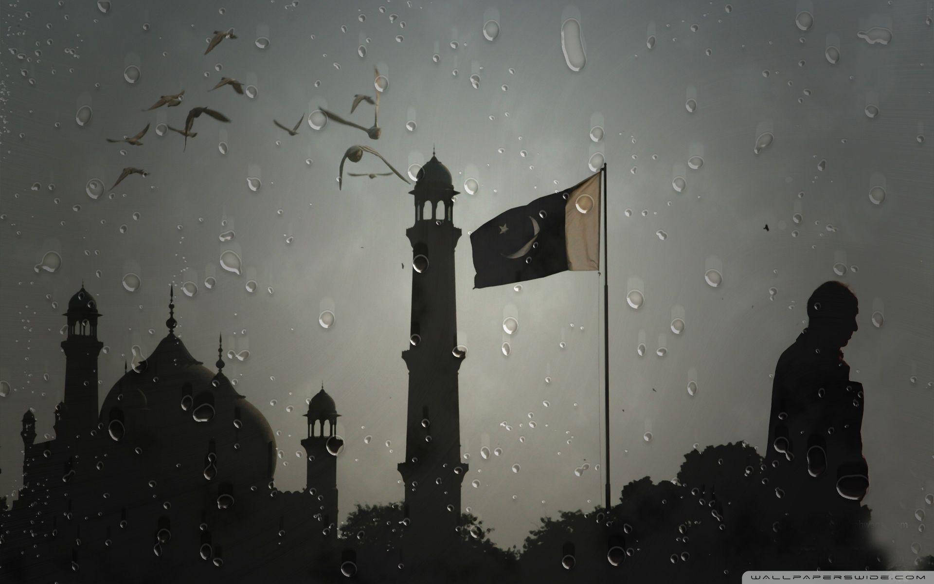 Pakistan 桌布 壁紙 — 透過濺滿雨水的玻璃看到的清真寺宣禮塔剪影和巴基斯坦國旗，鳥兒在頭頂飛翔。