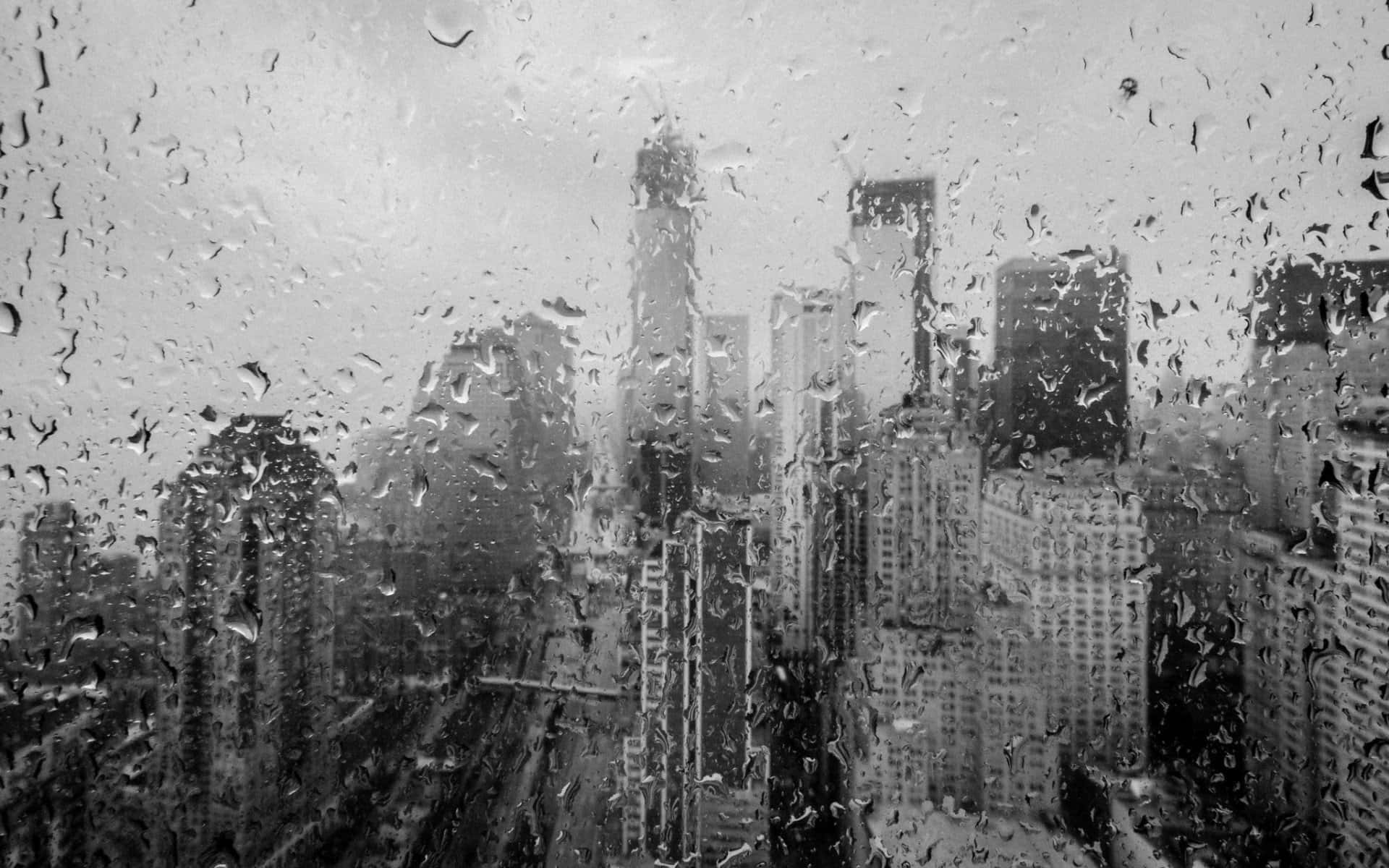 Black And White Storm 桌布 壁紙 — 透過濺滿雨水的窗戶看到的單色城市景觀，模糊的摩天大樓和流淌的水滴。