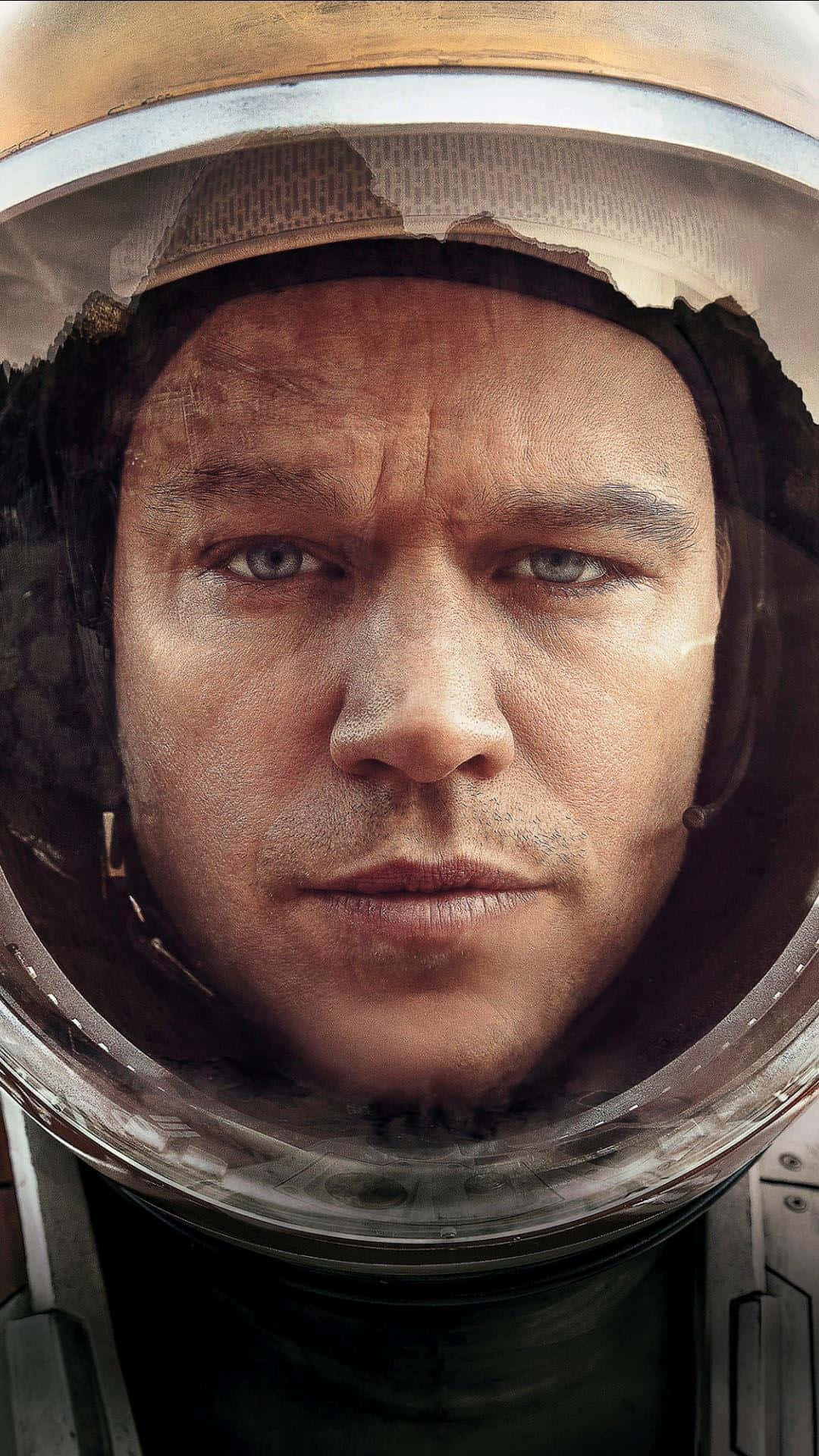 The Martian 桌布 壁紙 — 透過破裂的頭盔面罩近距離拍攝太空人的臉部，展現出強烈的決心。