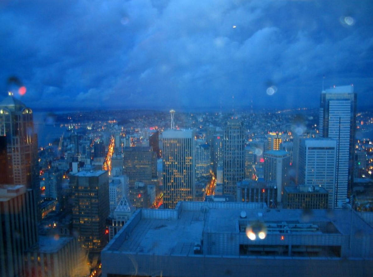 Rainy Day 桌布 壁紙 — 透過窗戶看到的雨夜城市景觀，水滴在街燈下閃爍。