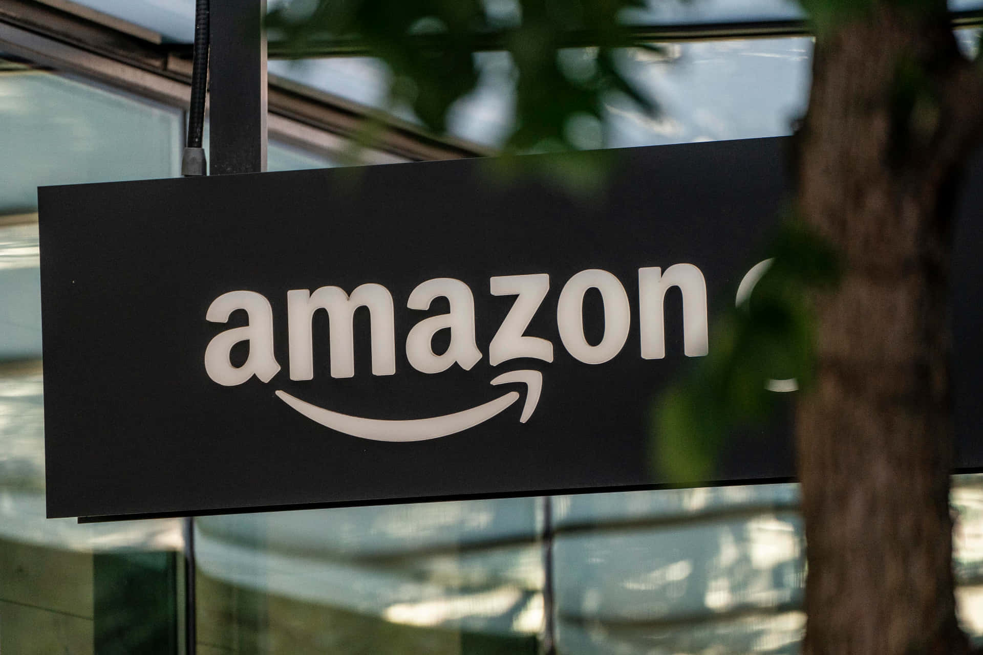透過玻璃建築附近的樹葉看到的Amazon標誌 — 亞馬遜 GIF 壁紙
