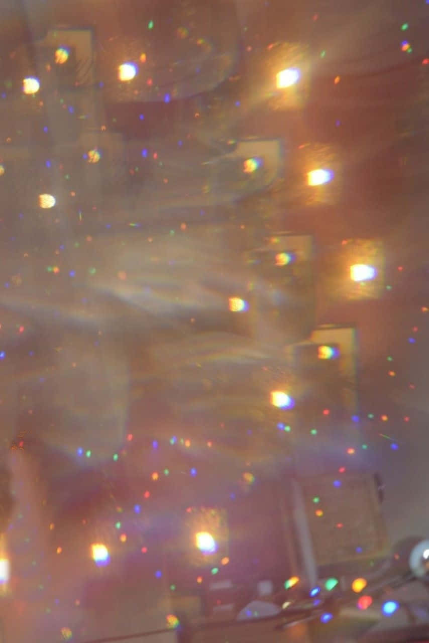 Sparkle Aesthetic 桌布 壁紙 — 透過閃爍表面看到的模糊景象，展現出溫暖燈光和彩色斑點，營造出夢幻般的抽象光芒。