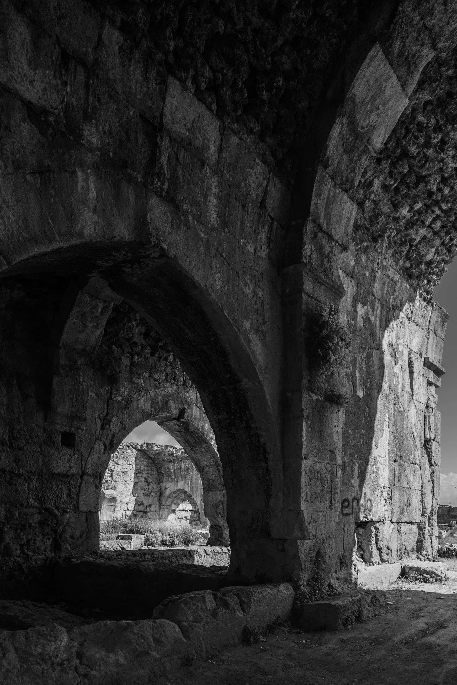 Middle Ages 桌布 壁紙 — 透過風化石拱門觀賞沐浴在戲劇性陽光下的古代遺跡黑白景觀。