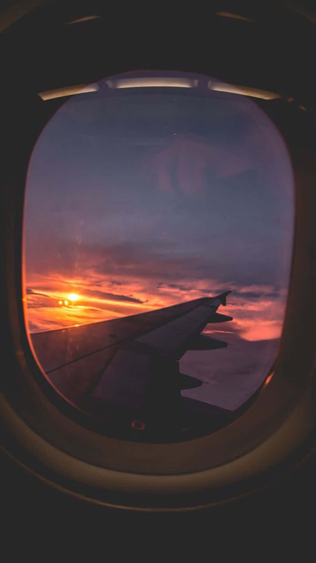 Airplane Window 桌布 壁紙 — 透過飛機窗戶看到的機翼剪影，背景是火紅的日落。