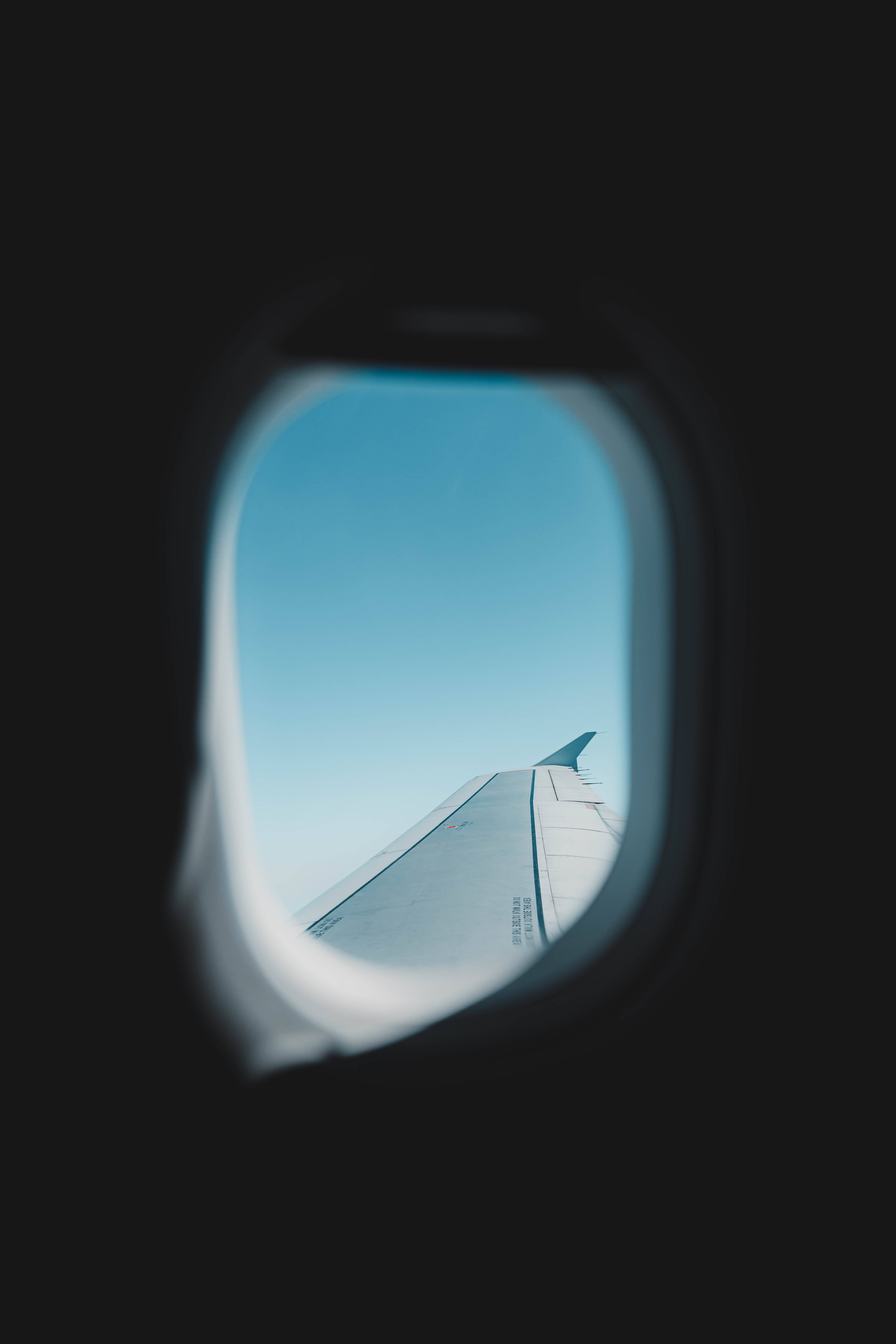 Plane 桌布 壁紙 — 透過飛機窗戶看到的飛機機翼，背景是白天飛行時的清澈藍天。