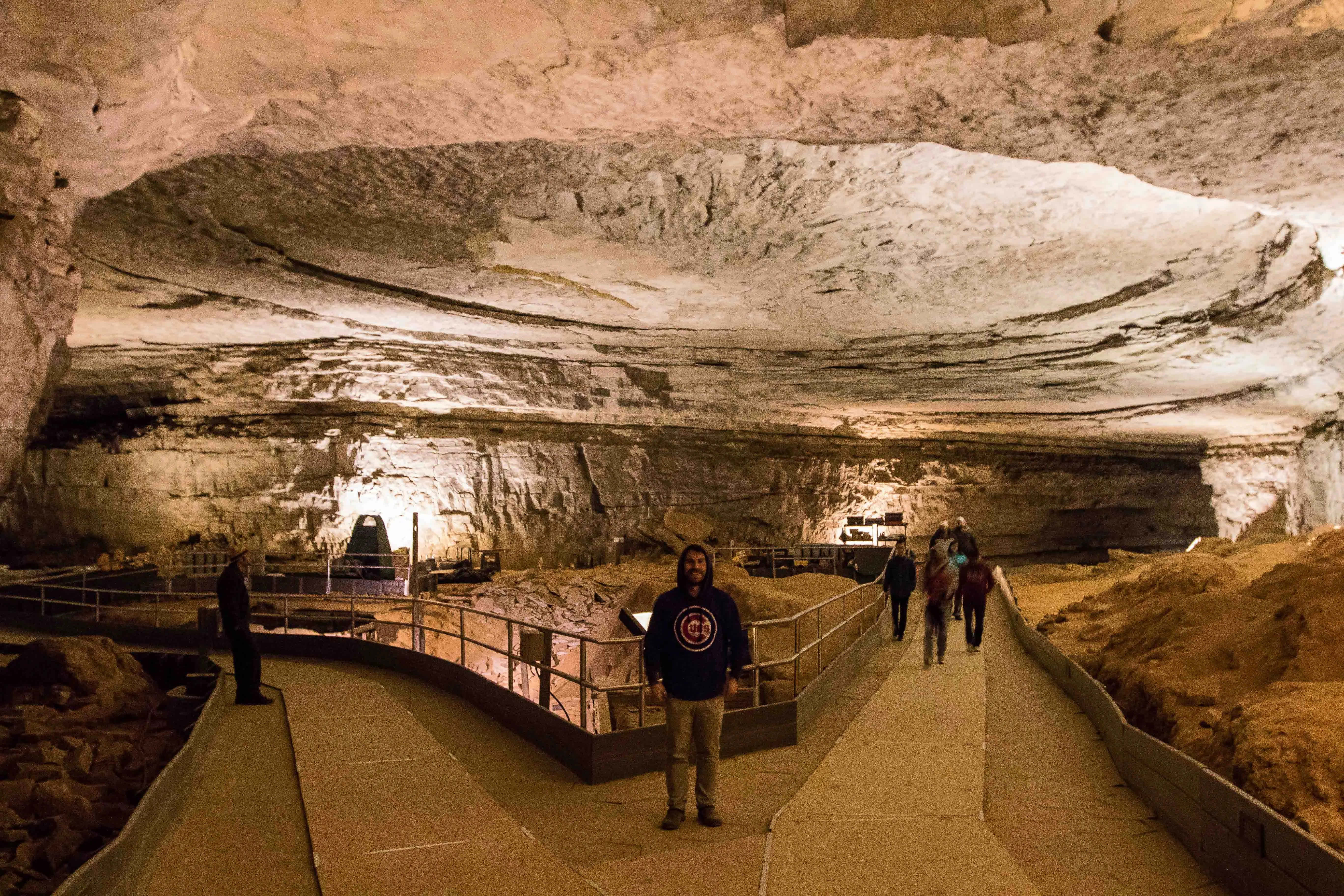 Cave 桌布 壁紙 — 遊客沿著一條燈光小徑穿過一個廣闊、紋理豐富的石灰岩洞穴，洞穴內有高聳的岩石 formations。