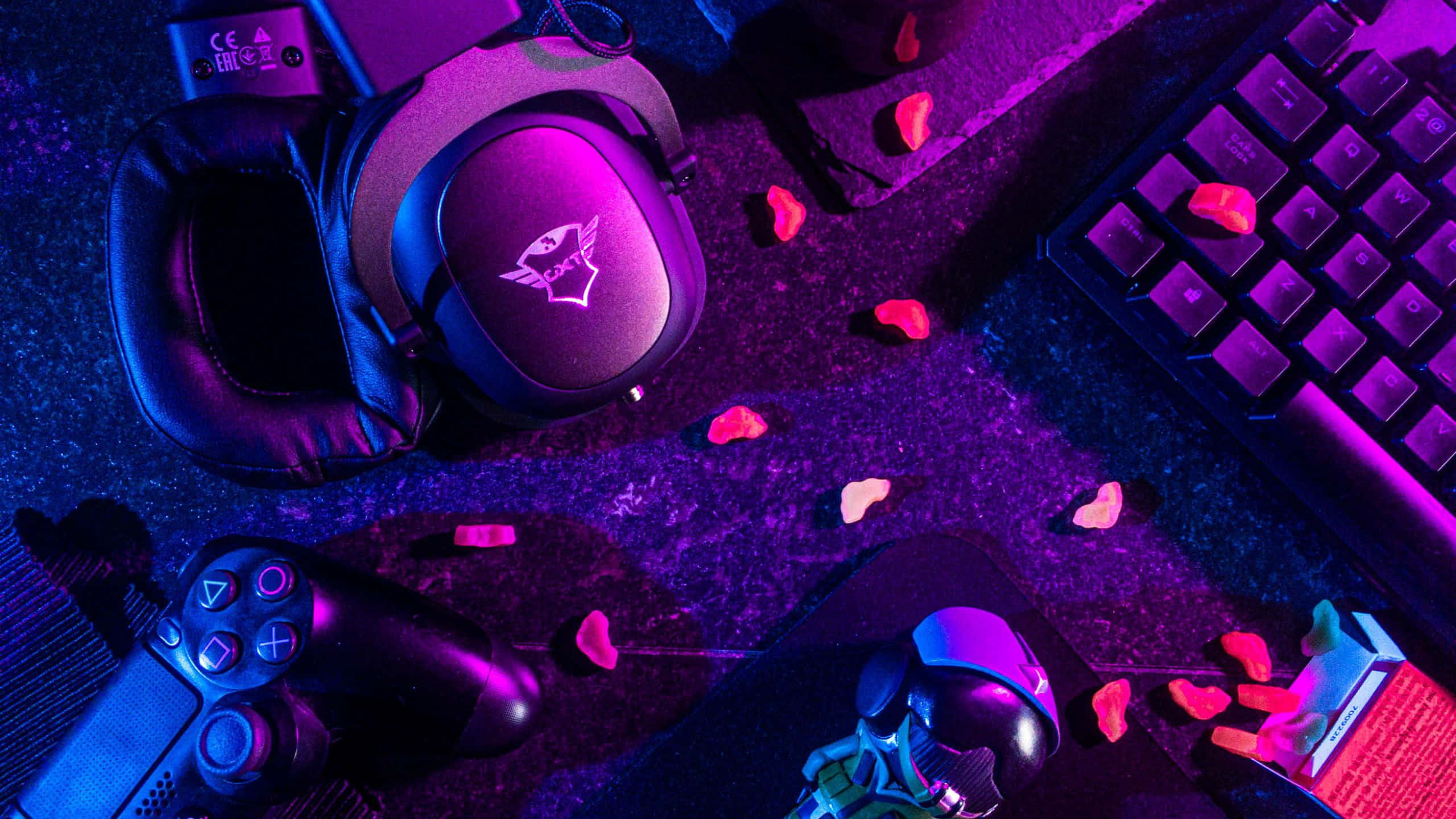 Gaming Banner 桌布 壁紙 — 遊戲裝備包括耳機控制器和鍵盤，沐浴在霓虹紫和粉紅光中，散落著糖果心。