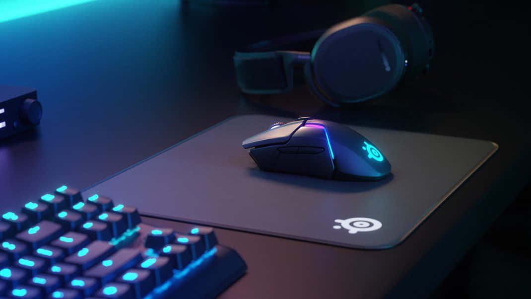 Gaming Mouse 桌布 壁紙 — 遊戲設置，在黑暗的桌子上有發光藍色鍵盤、滑鼠和耳機，在霓虹燈光下。