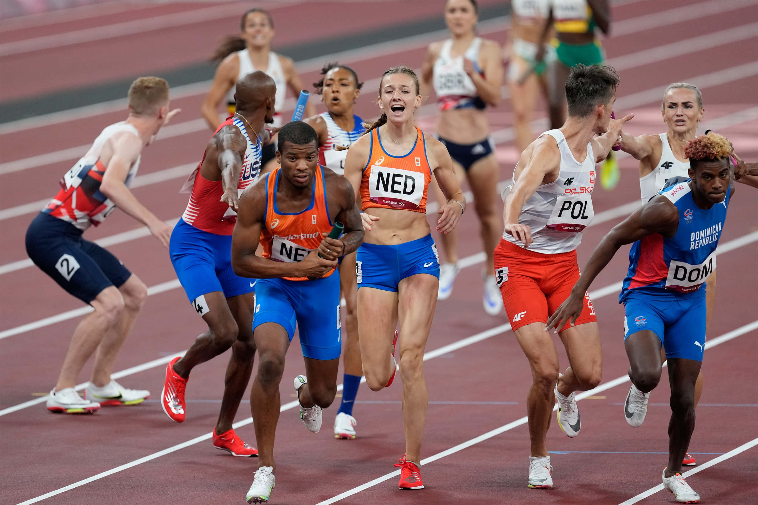 運動 桌布 壁紙 — 運動員穿著鮮豔的制服在紅色跑道上激烈衝刺，進行一場競爭激烈的比賽，表情專注，動作動態十足。