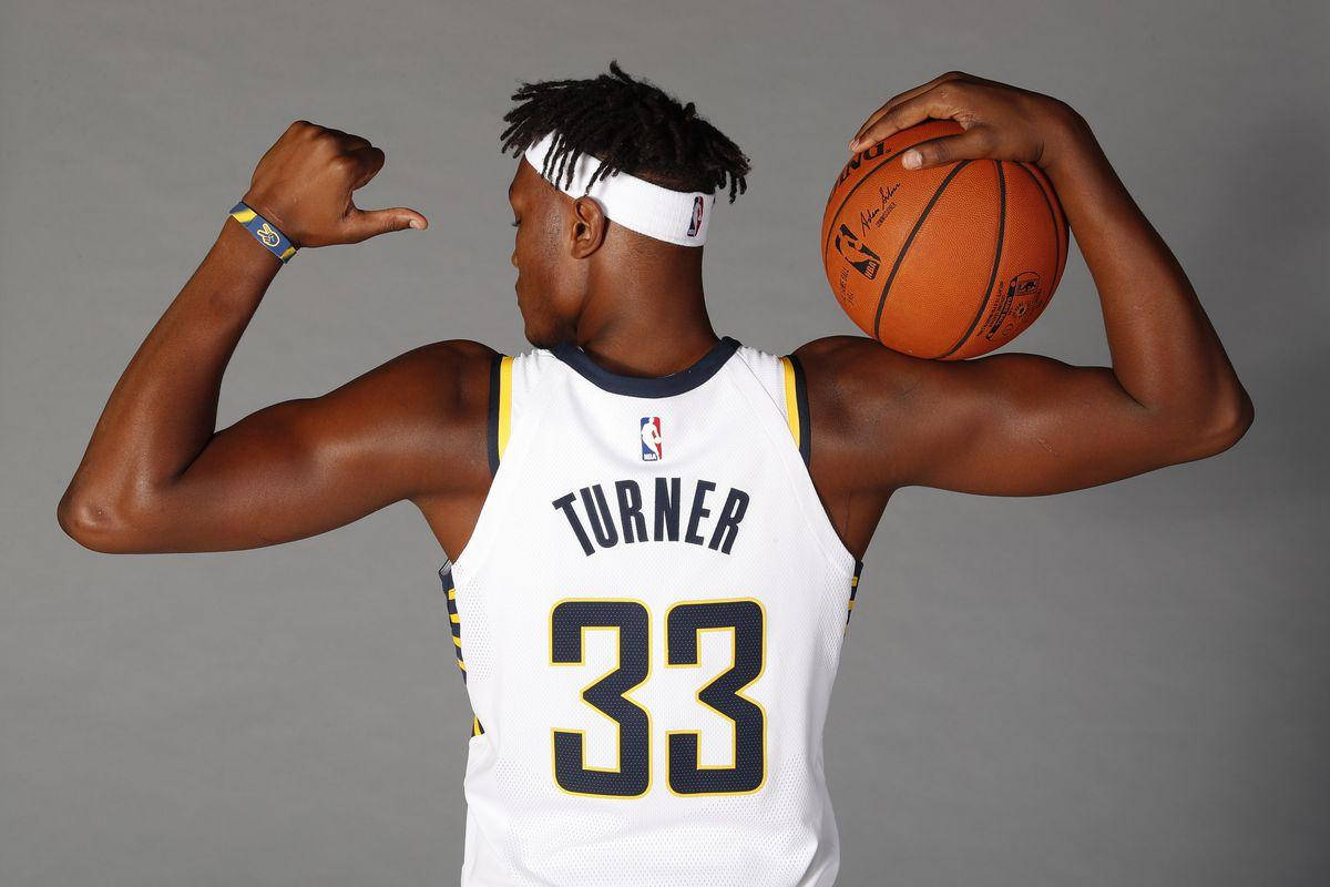 myles turner 桌布 壁紙 — 運動型籃球運動員 Turner 33 號在灰色工作室背景下，將籃球舉過肩膀，展示肌肉。