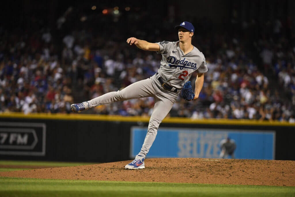 walker buehler 桌布 壁紙 — 道奇隊棒球投手在燈光照射的投手丘上投球，背景是模糊的人群。