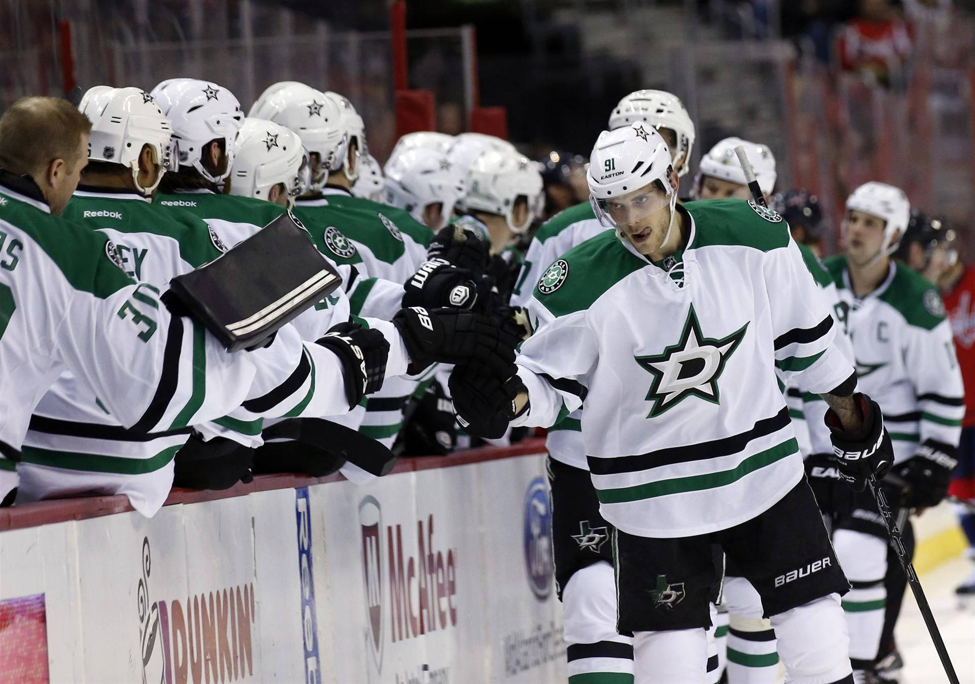 Dallas Stars 桌布 壁紙 — 達拉斯星隊的冰球運動員穿著綠色和白色球衣，在比賽期間於場邊與隊友擊掌。