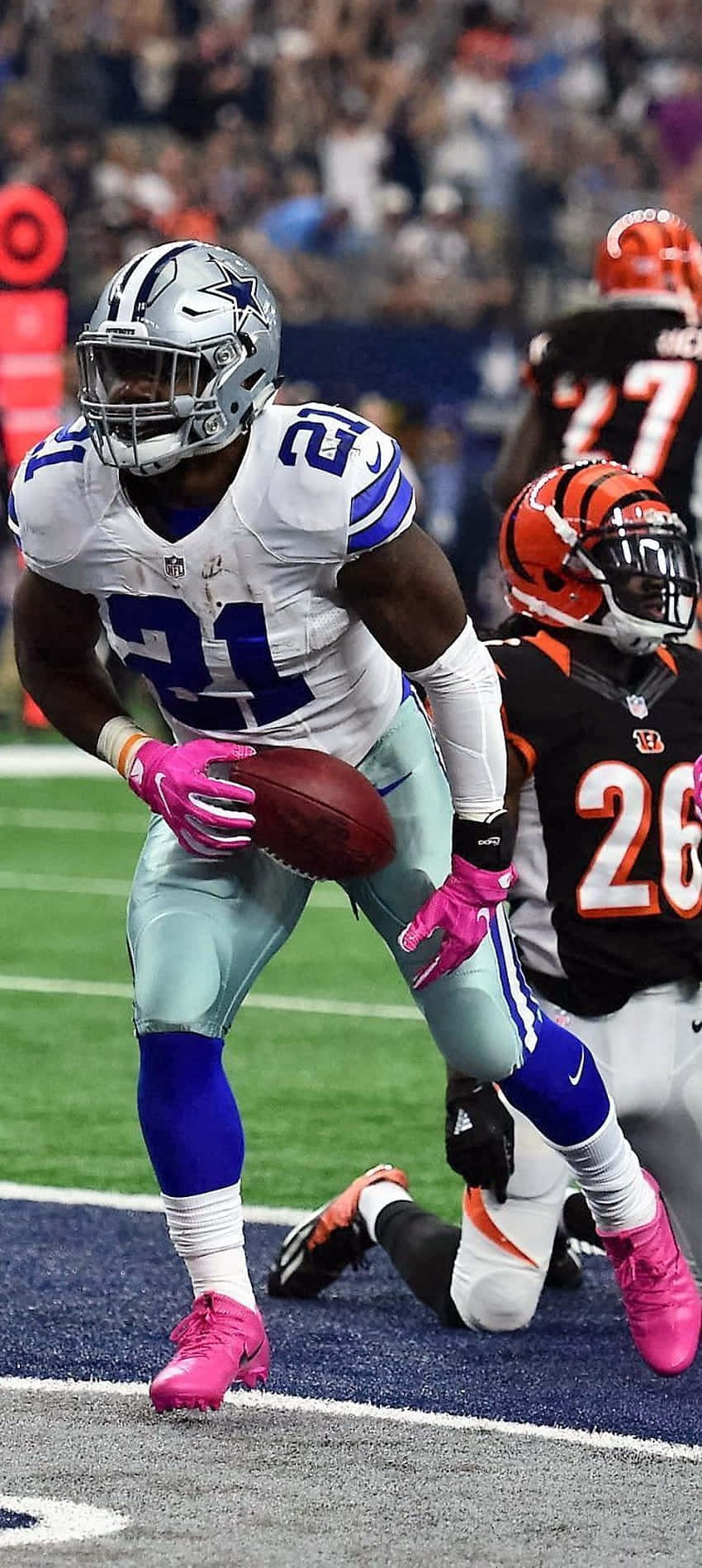 Dallas Cowboys iPhone 桌布 壁紙 — 達拉斯牛仔隊21號球員在夜間NFL比賽中穿著鮮豔的粉紅色裝備持球奔跑。