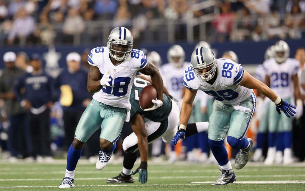 Dallas Cowboys Players 桌布 壁紙 — 達拉斯牛仔隊88號球員帶球奔跑，隊友89號在夜間比賽中防守擒抱。