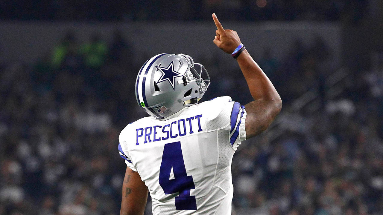 Dak Prescott 桌布 壁紙 — 達拉斯牛仔隊四分衛Dak Prescott身穿白色4號球衣，在夜間比賽中慶祝時向上指。