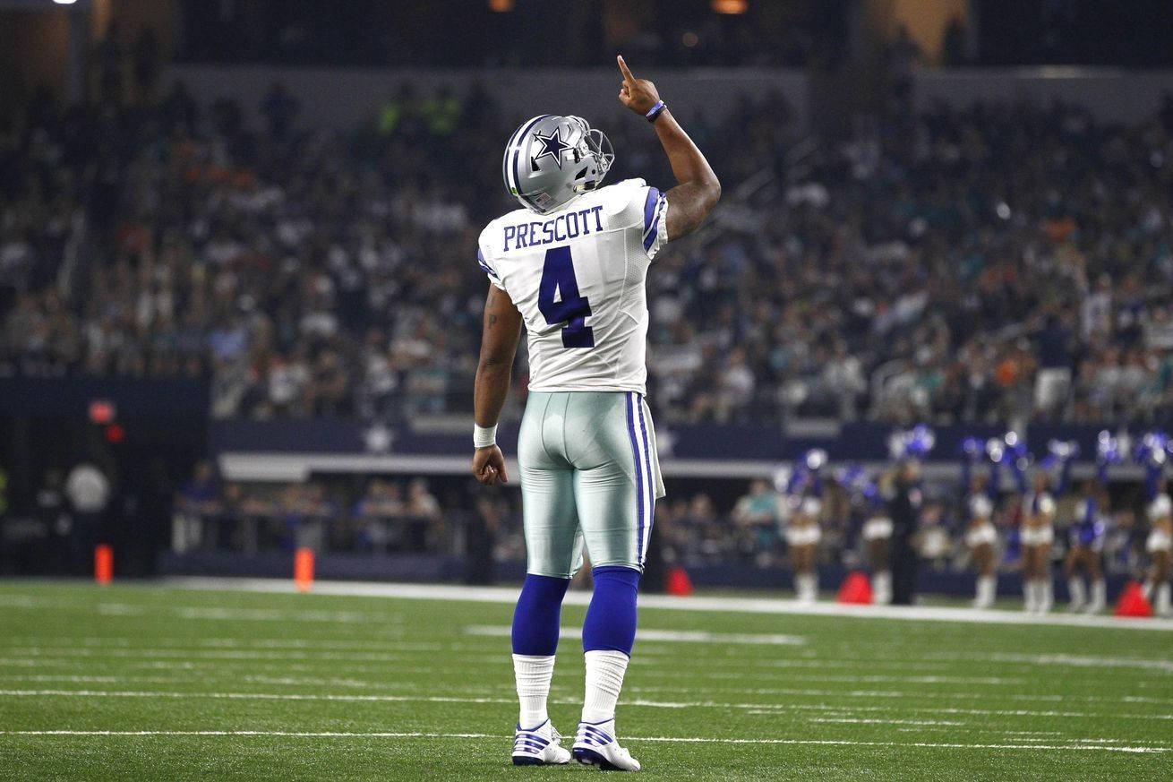 Dak Prescott 桌布 壁紙 — 達拉斯牛仔隊四分衛達克·普雷斯科特身穿白色4號球衣，在夜間燈光球場上向上指。