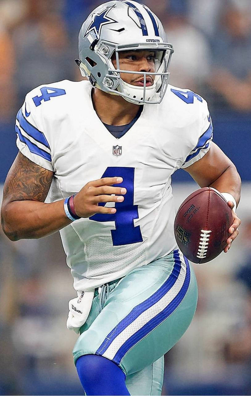 Dak Prescott 桌布 壁紙 — 達拉斯牛仔隊四分衛達克·普雷斯科特身穿白色和藍色球衣，在比賽期間於球場燈光下持球奔跑。