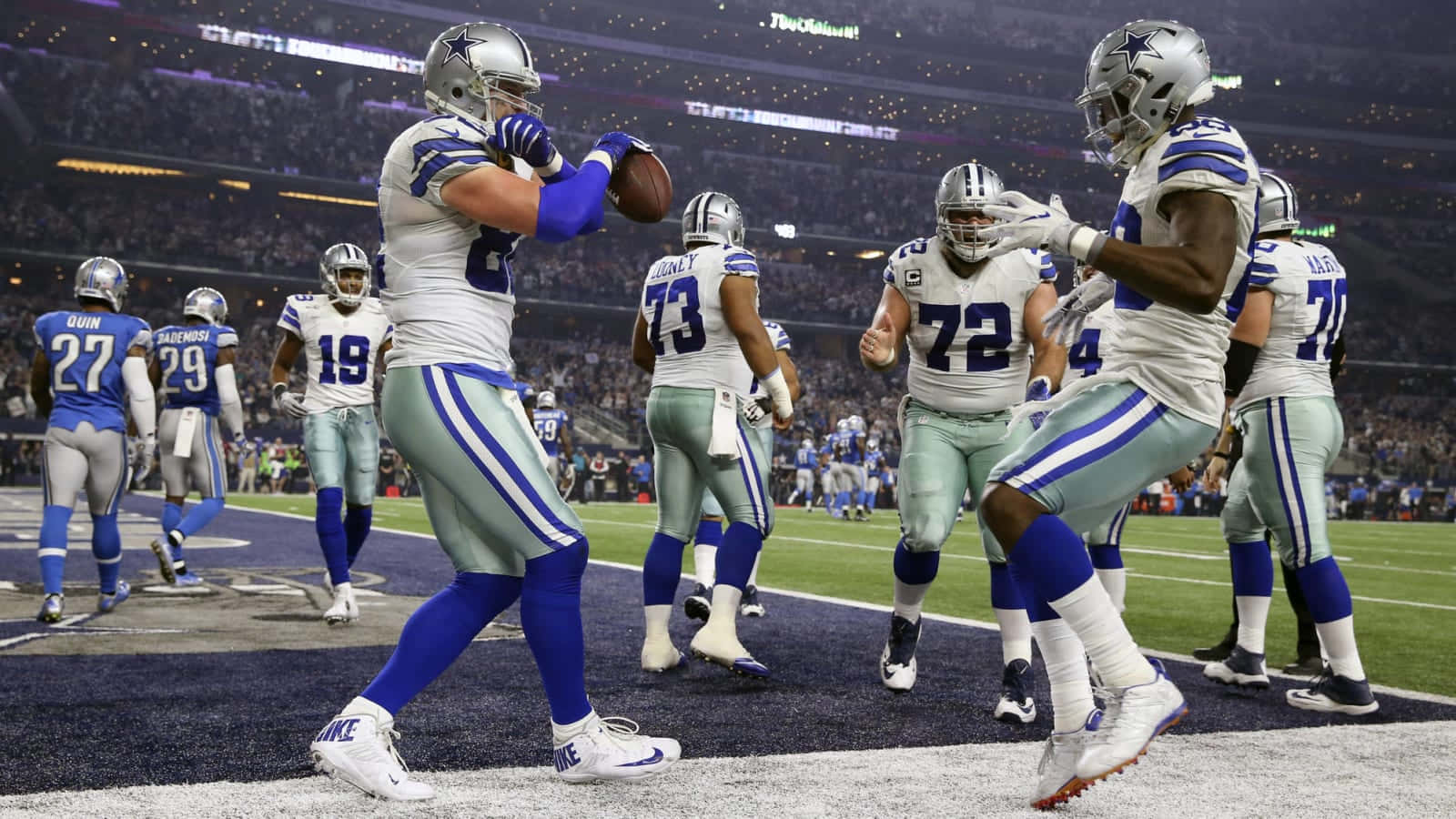 Dallas Cowboys Players 桌布 壁紙 — 達拉斯牛仔隊球員在體育場燈光下，於明亮照明的足球場上慶祝達陣。
