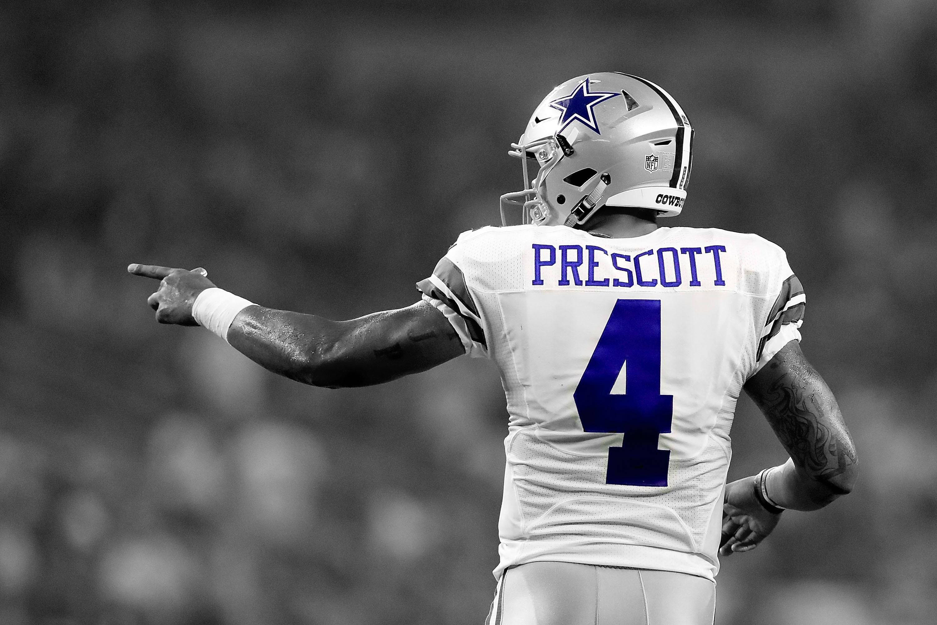 Dak Prescott 桌布 壁紙 — 達拉斯牛仔隊的四分衛身穿白色球衣，藍色4號，在模糊的球場背景下於比賽中向前指點。